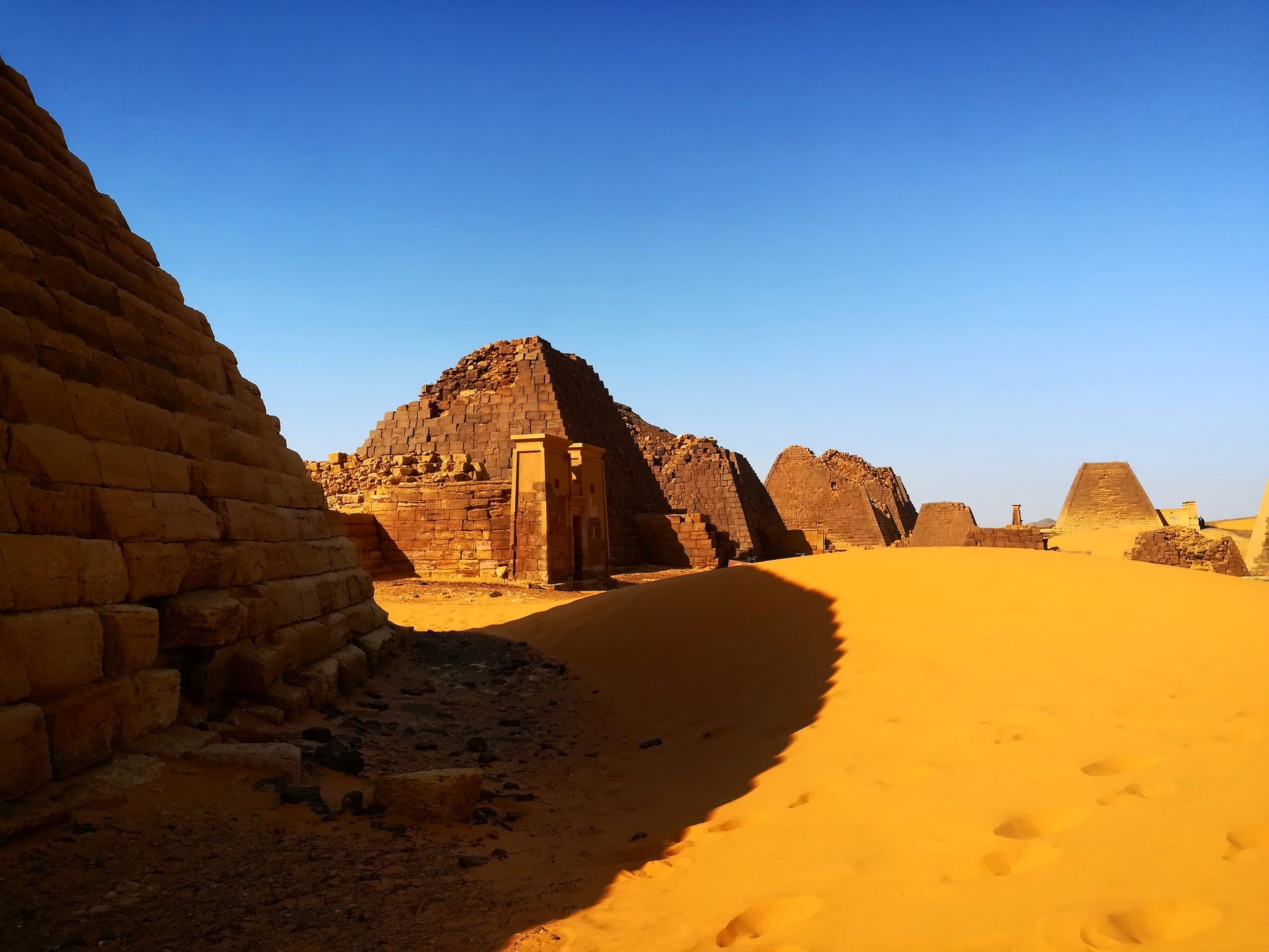 Rows of narrow, steep-sided stone pyramids in the desert at sunset