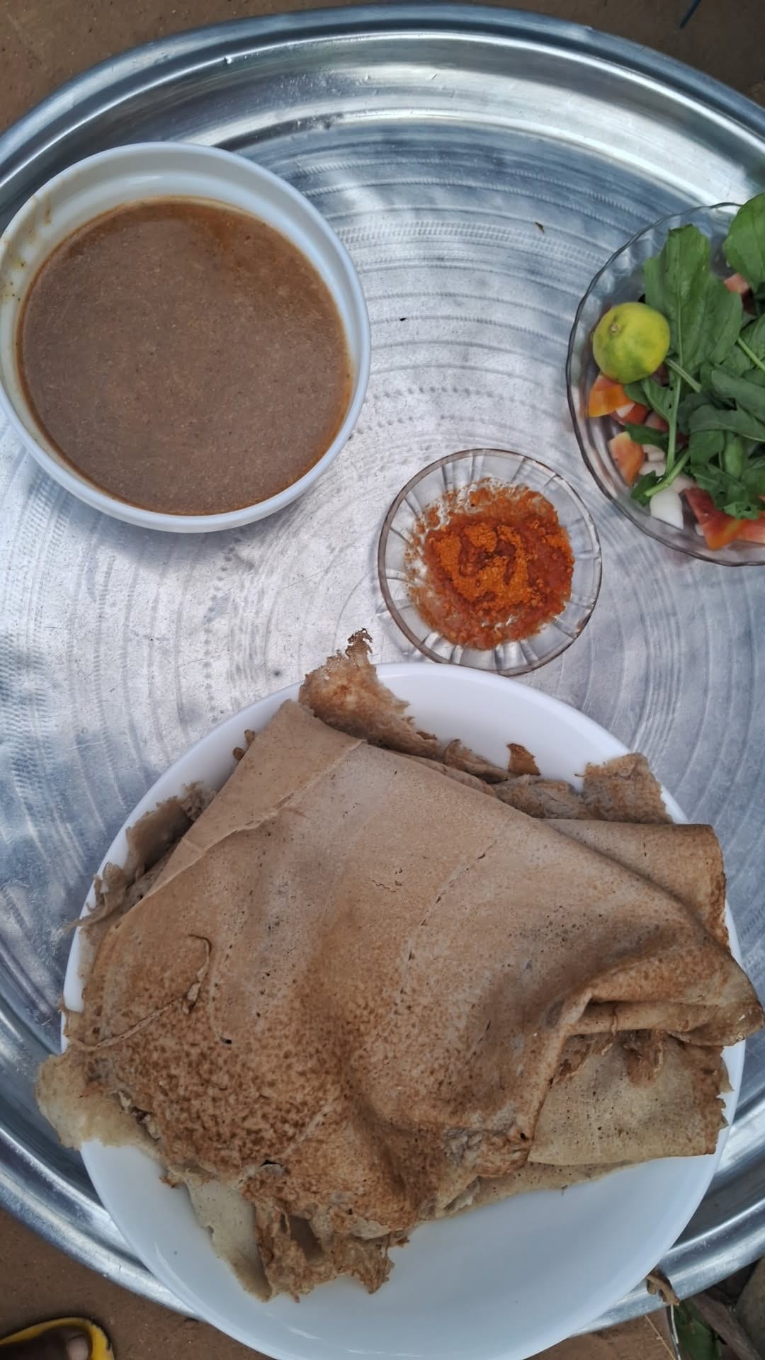 A tray of flatbread with stew and salad