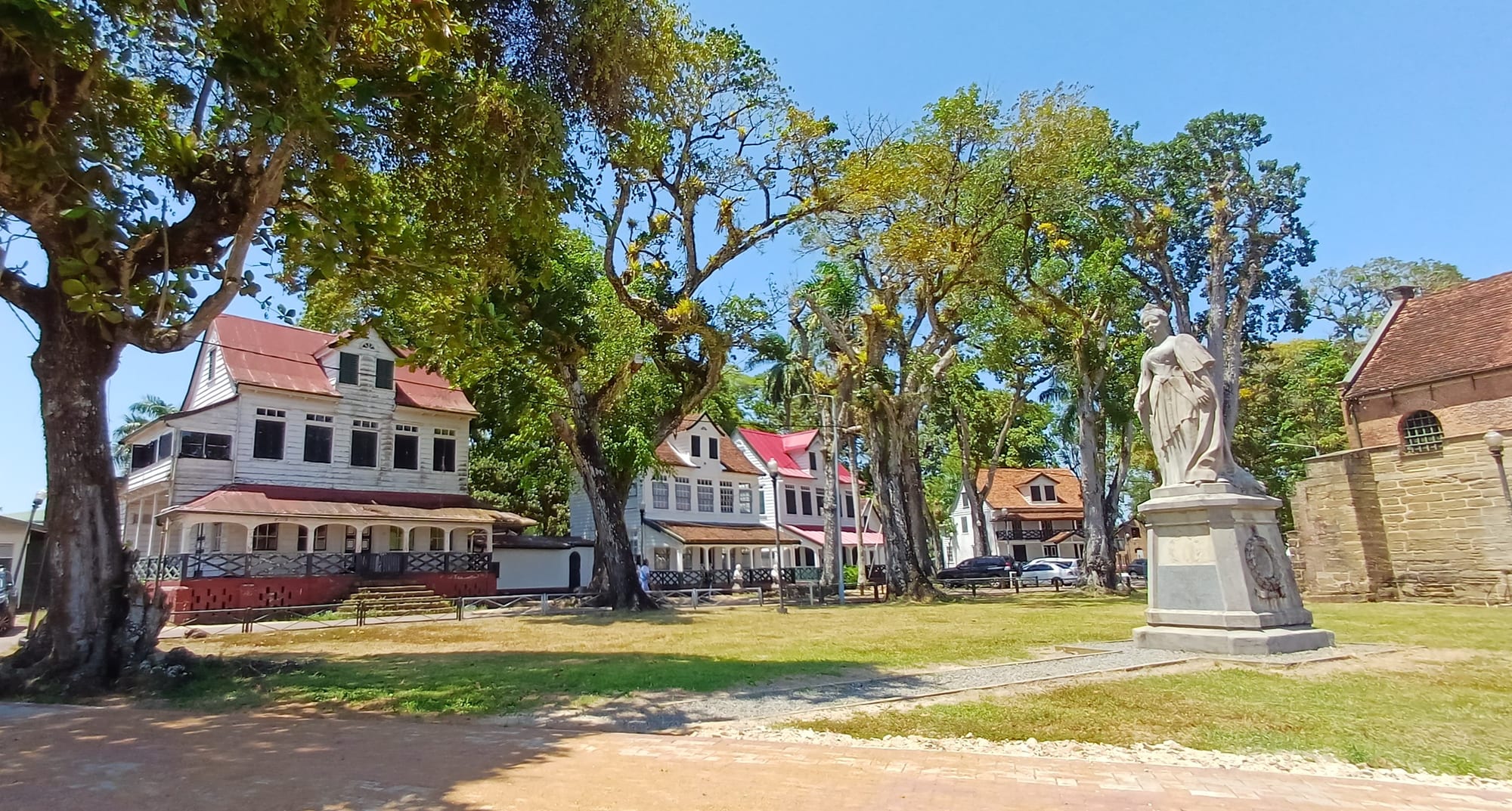 A row of white wooden colonial-era buildings along a tree-lined street