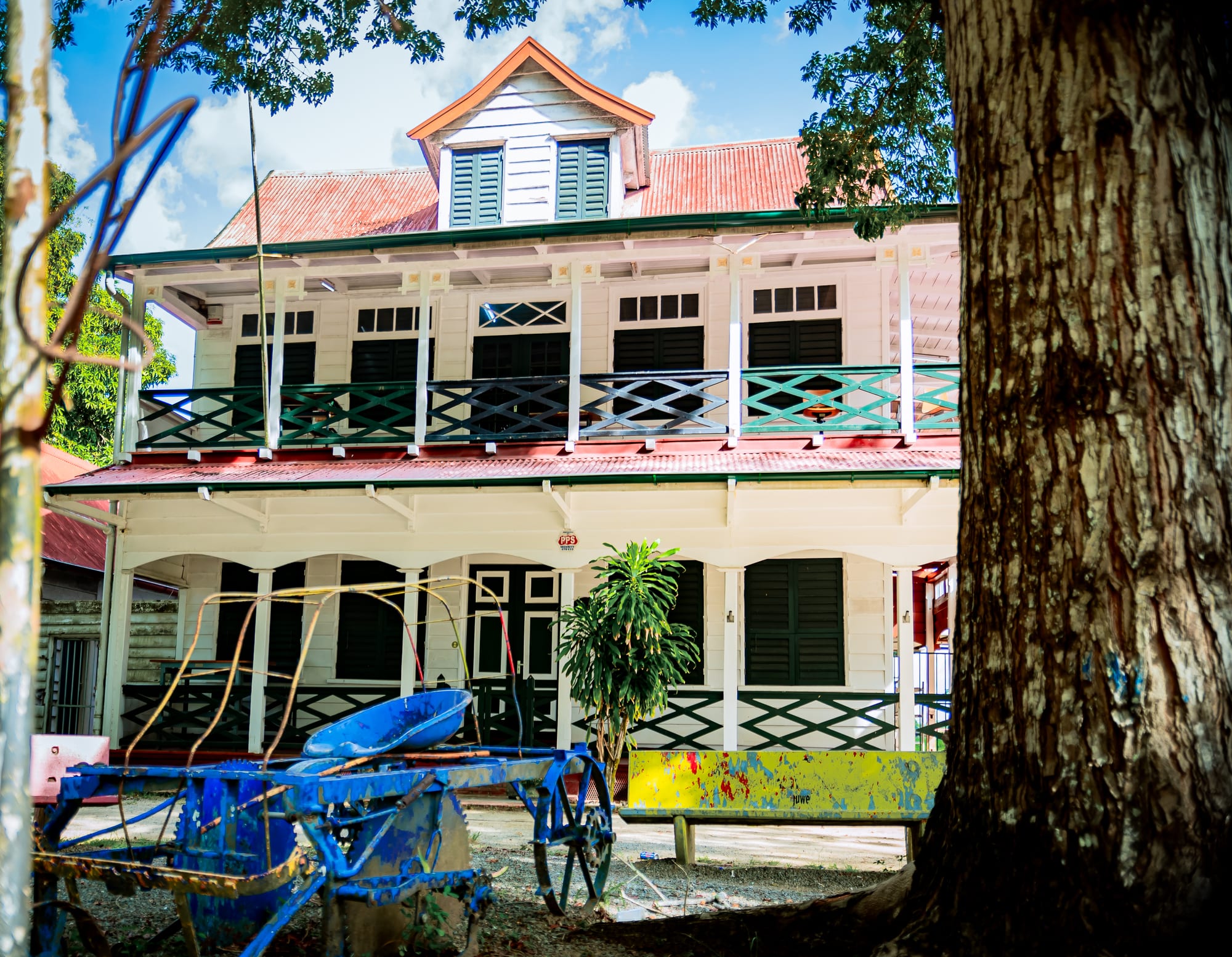 A tall white Dutch colonial wooden building with green shutters and a double staircase in Paramaribo