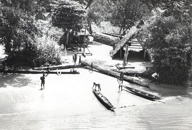 Thatched wooden houses of a Maroon village along the forested bank of the Suriname River, 1955
