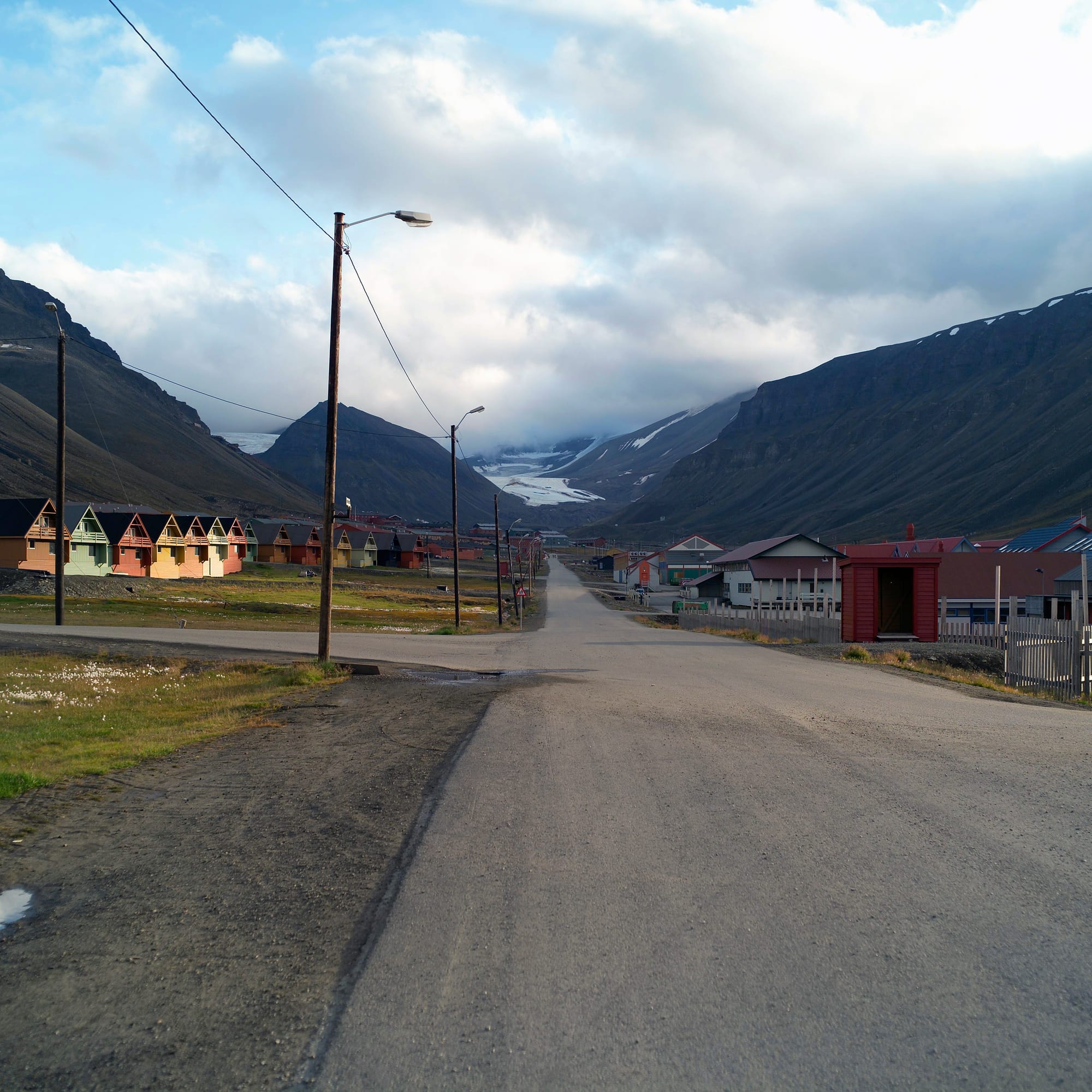 A small Arctic settlement of colourful buildings surrounded by snow-covered mountains
