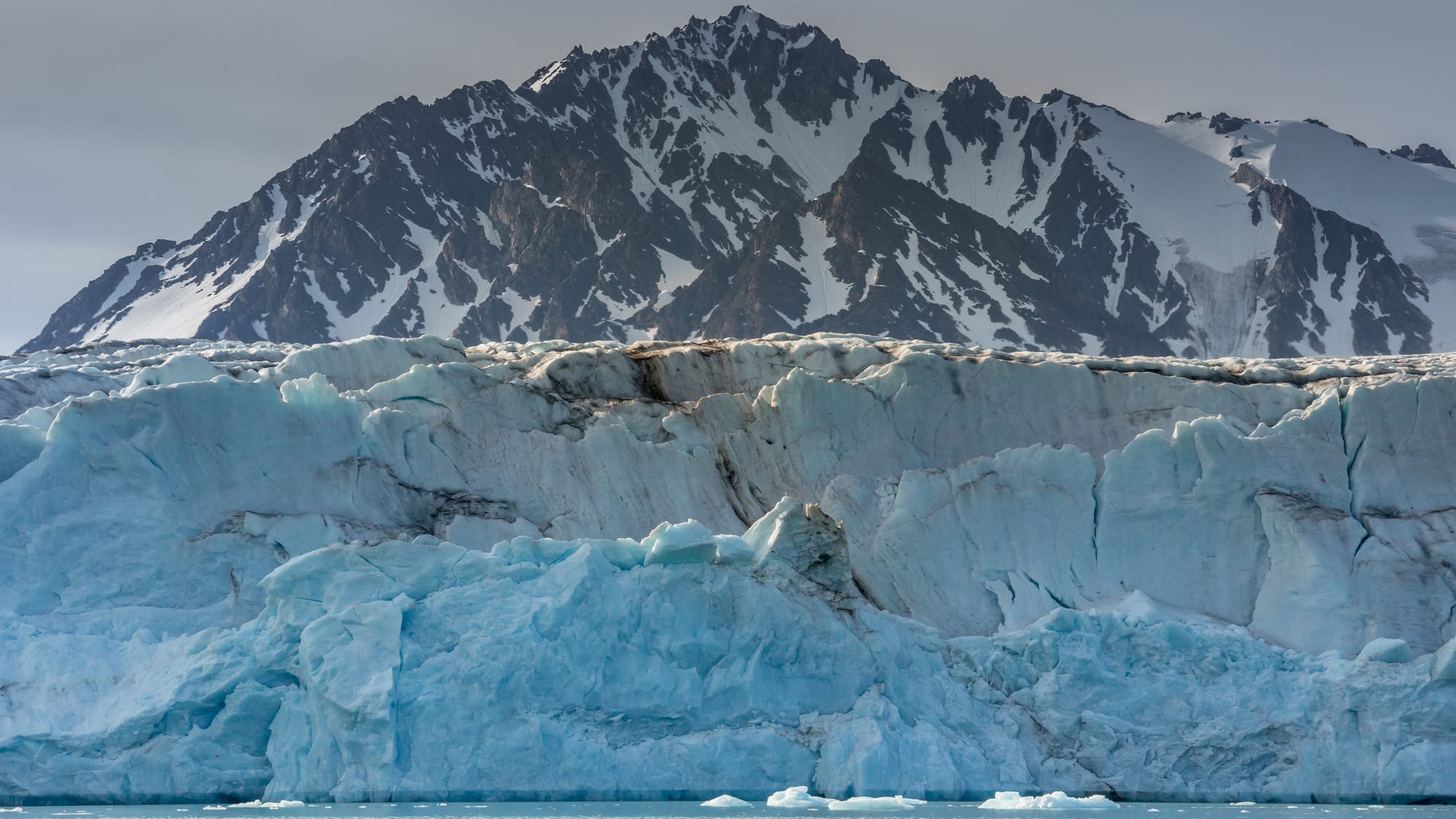 A glacier front meeting a calm Arctic fjord