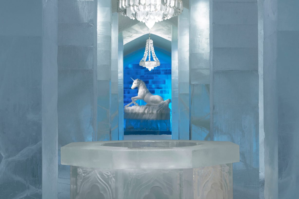 An elaborately carved ice sculpture hall lit with blue light