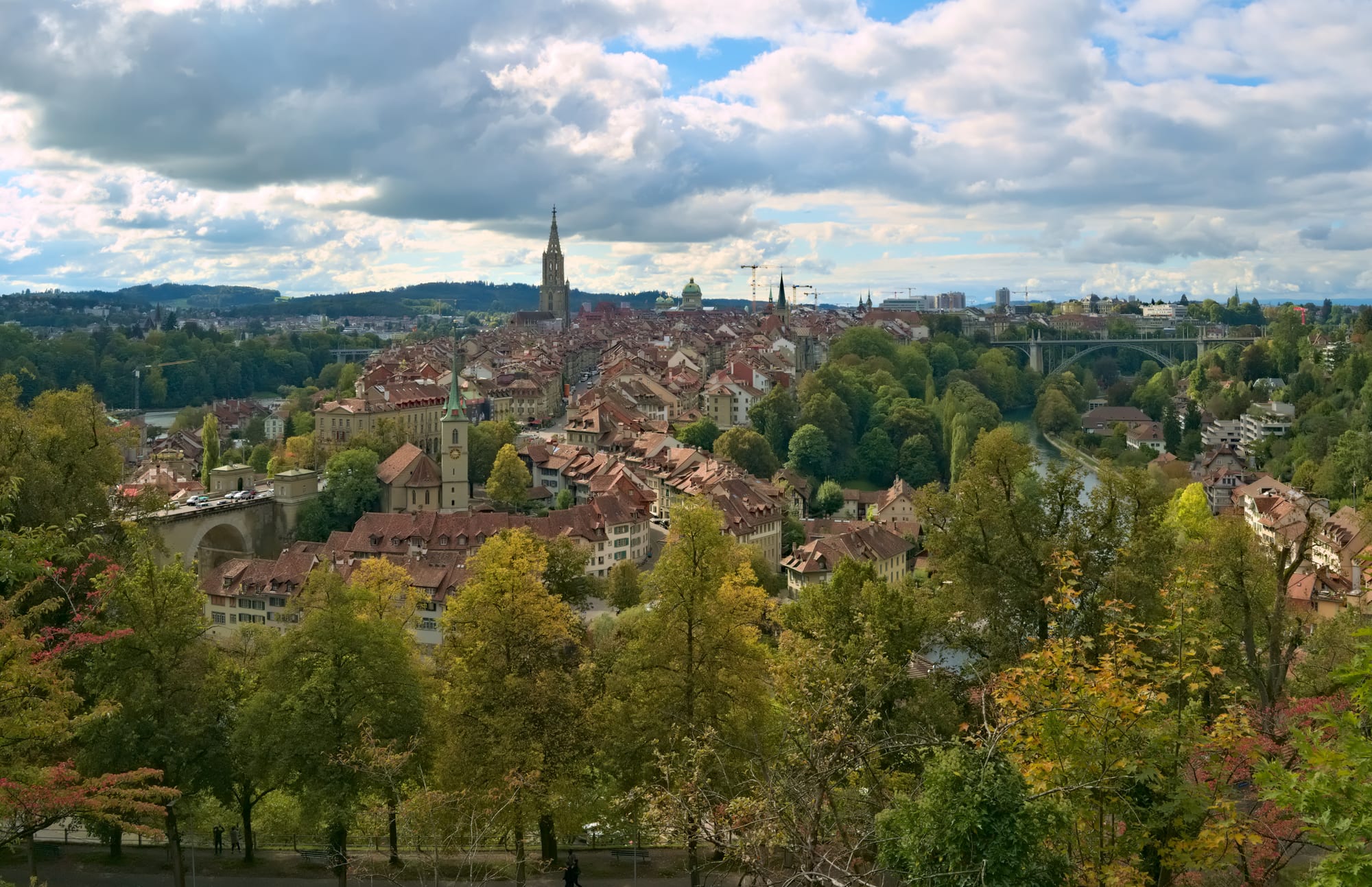 A panoramic view over a historic city with red-tiled roofs bordered by a winding river
