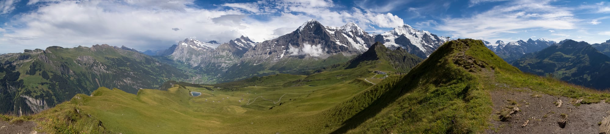 A dramatic view over green alpine valleys and snow-capped peaks