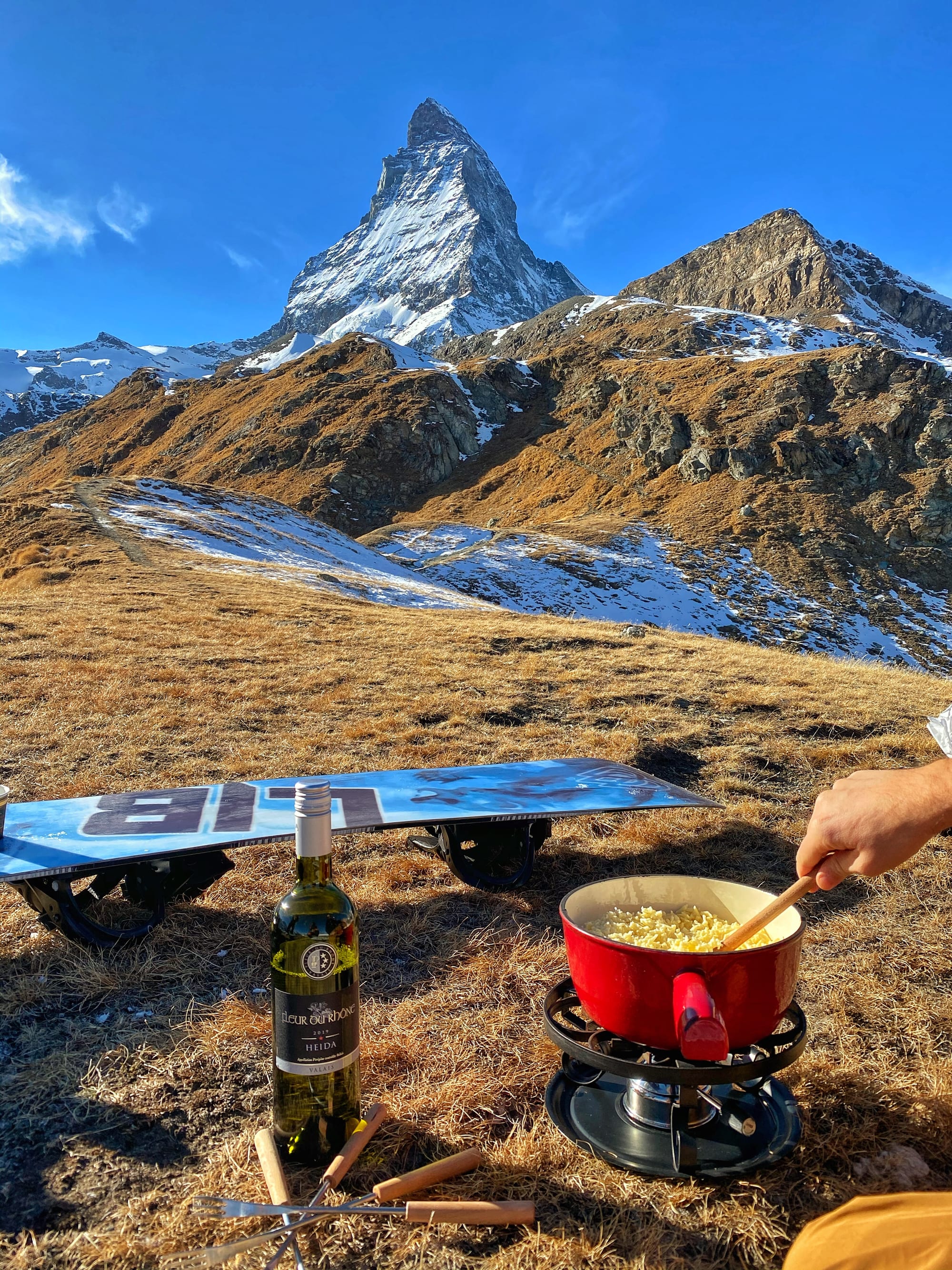A pot of melted cheese fondue with a mountain in the background