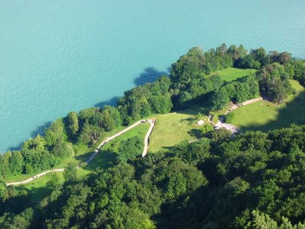 A green sloping alpine meadow above Lake Lucerne, ringed by trees and mountains