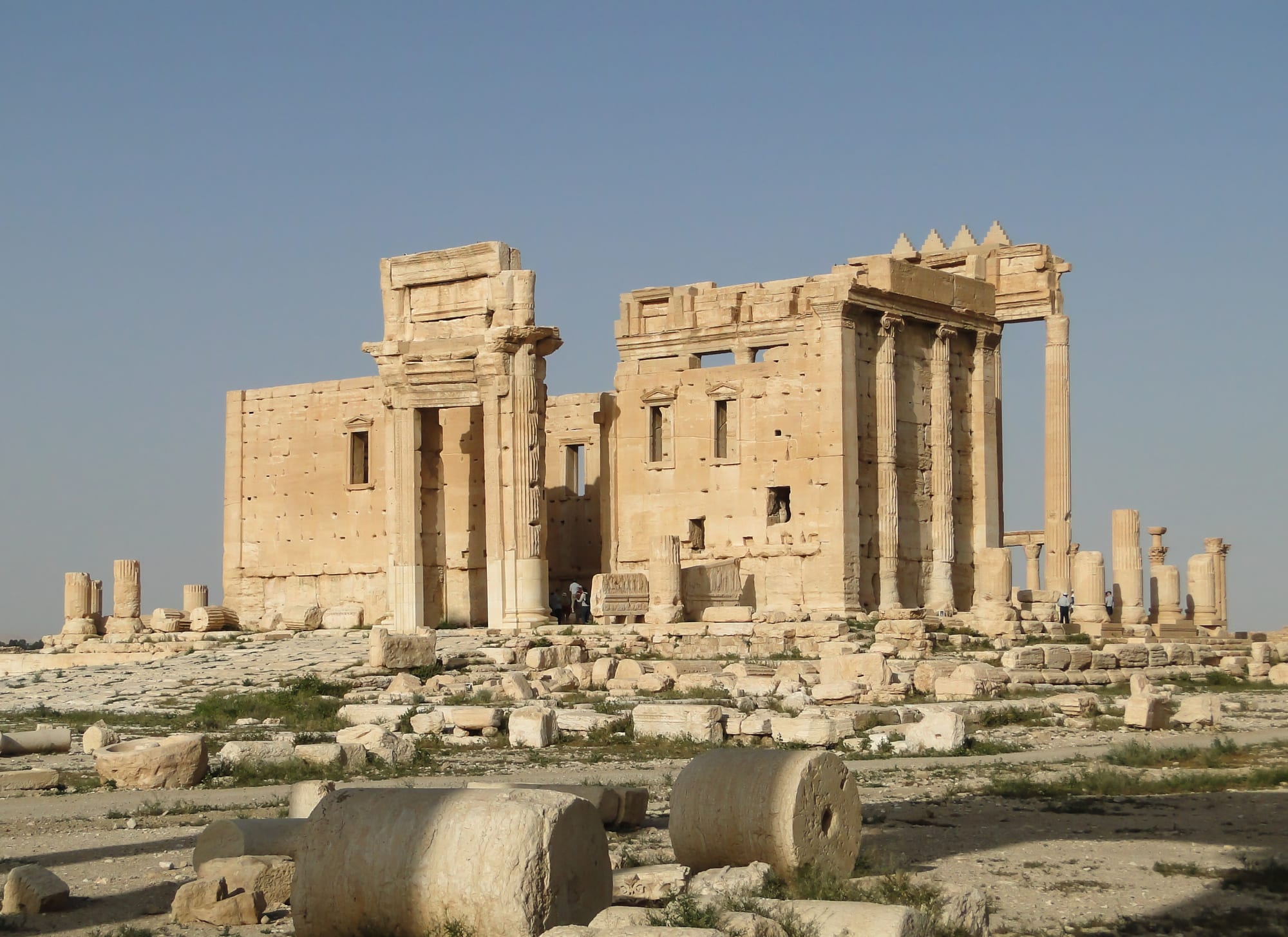The ruins of a large ancient temple with columns in a desert landscape