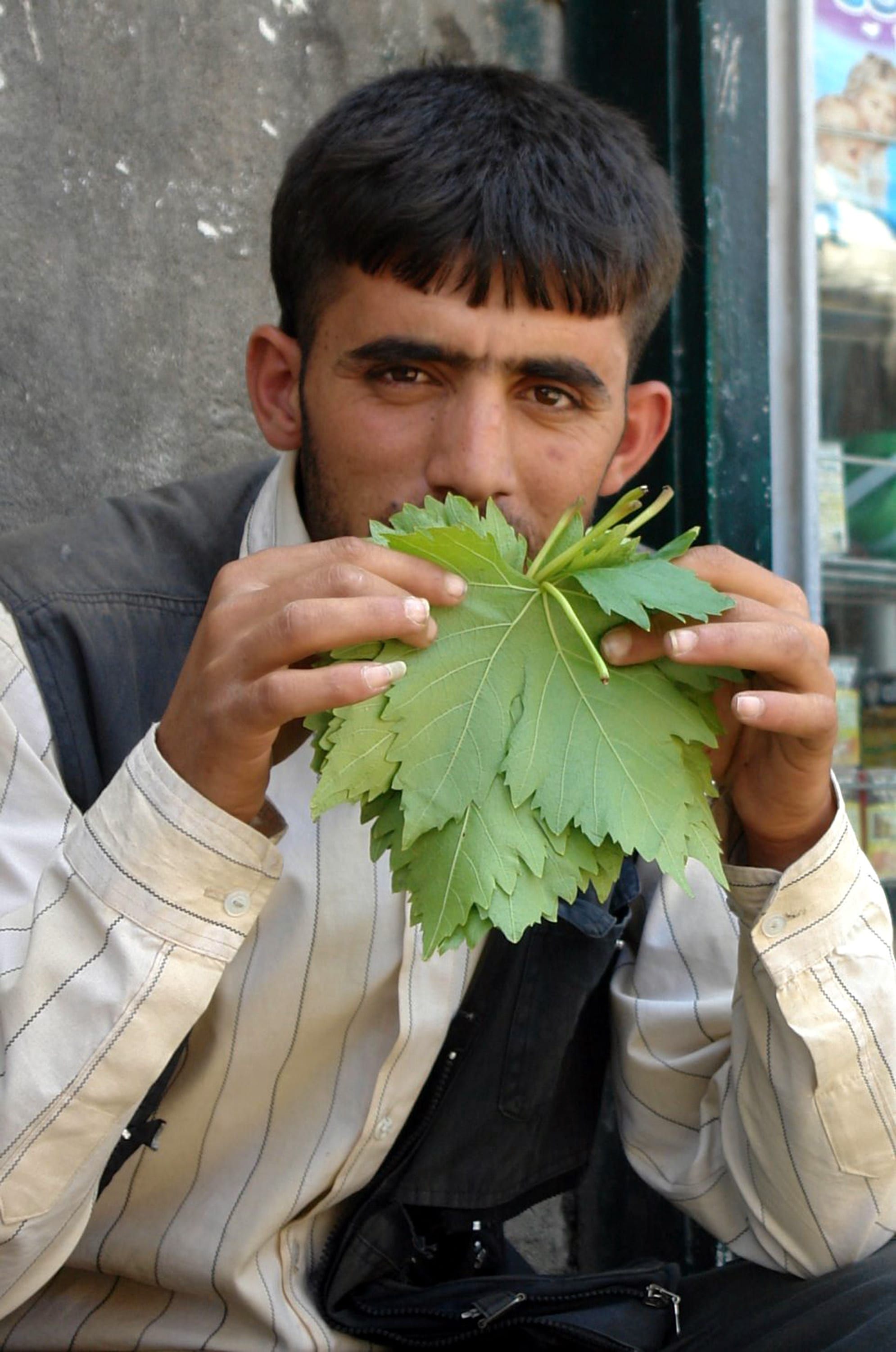 A vendor selling grape leaves at a covered market