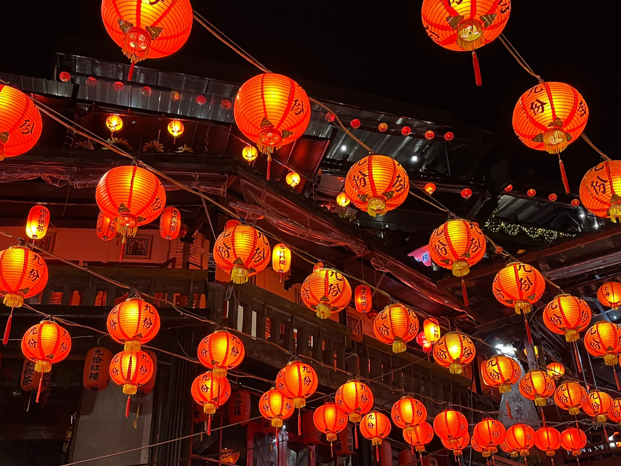 A steep hillside town with red lanterns strung along narrow lanes