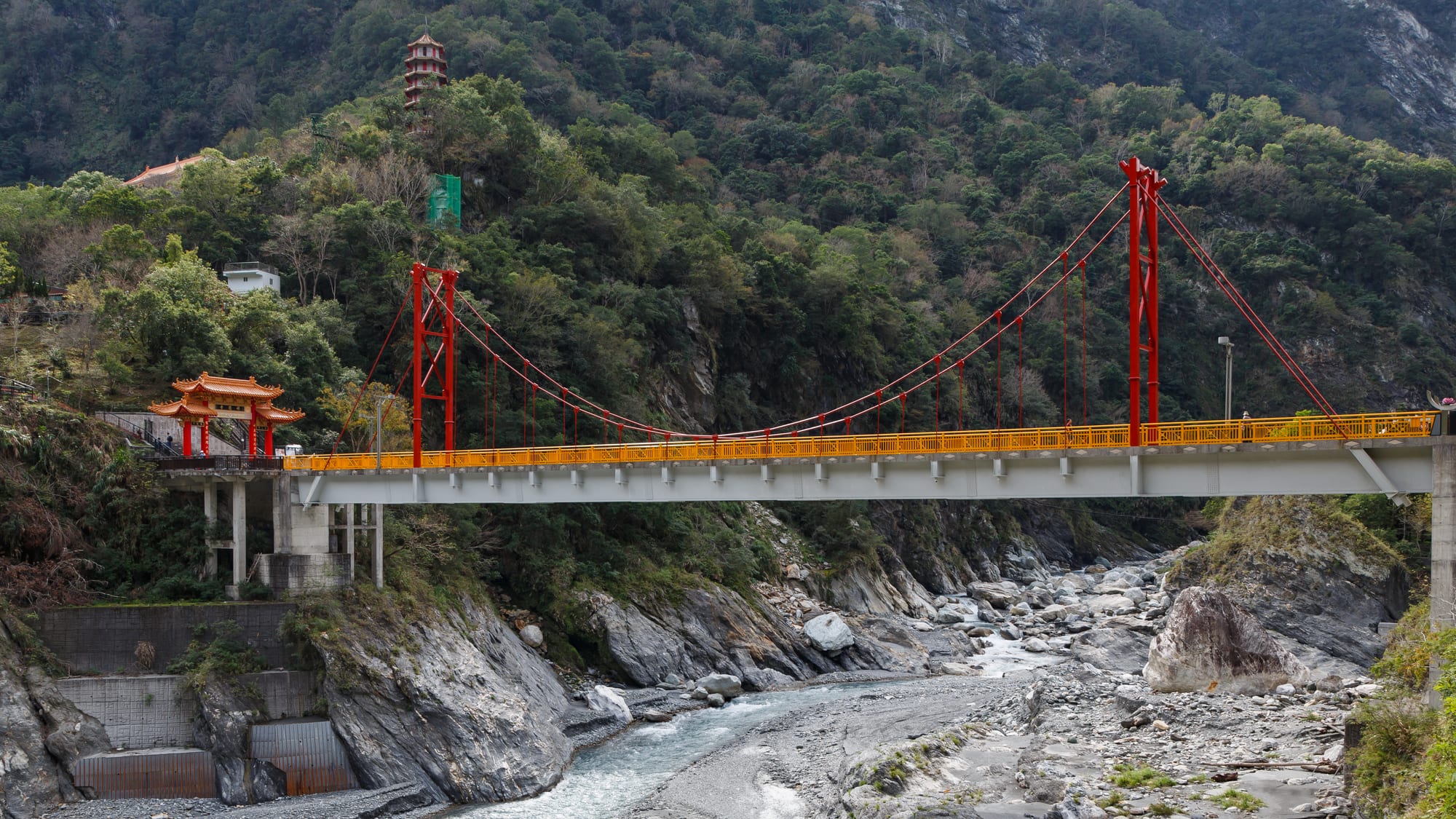 A dramatic marble gorge with a bridge crossing a turquoise river