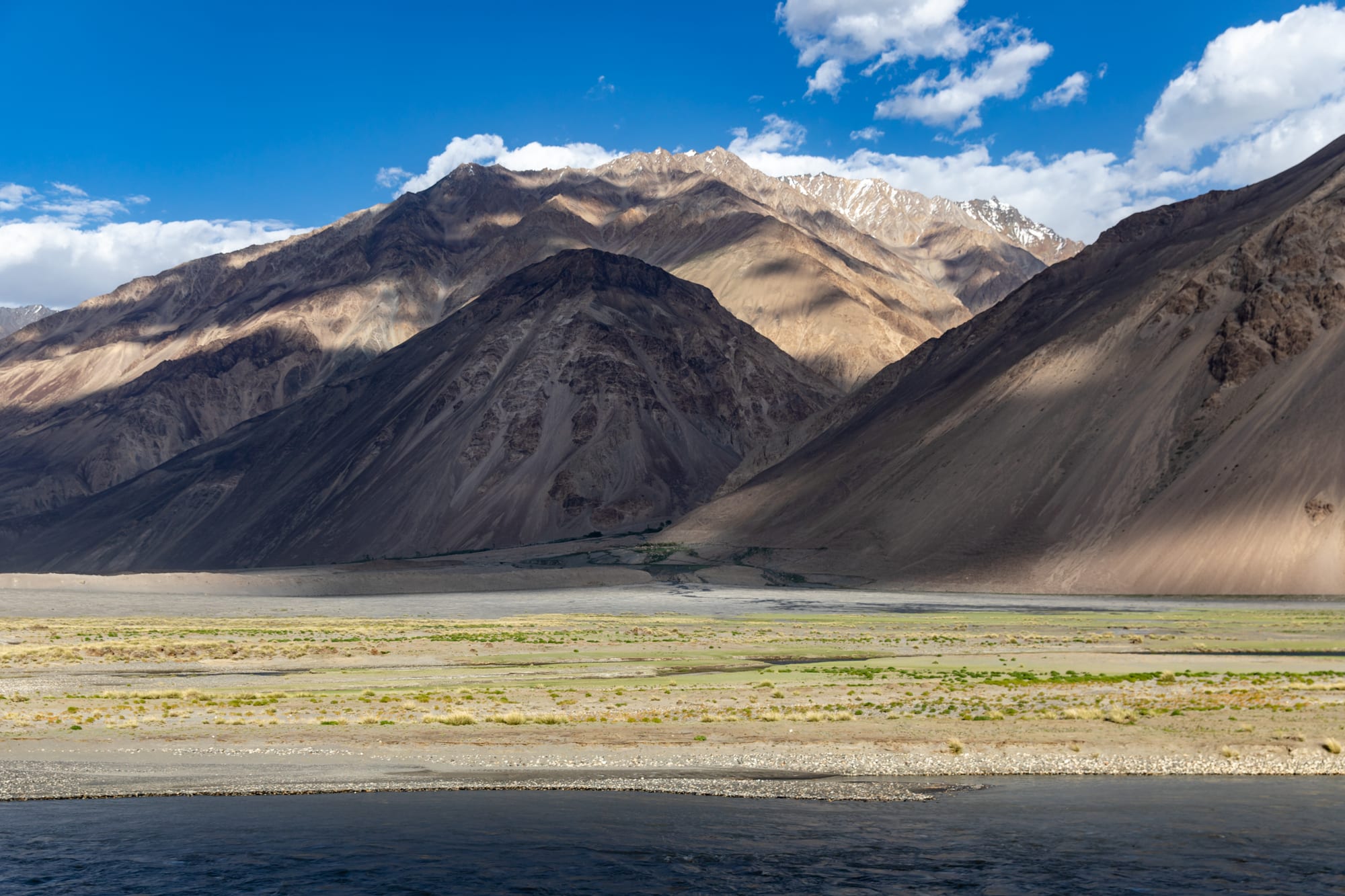 A narrow river valley with villages set against towering mountains