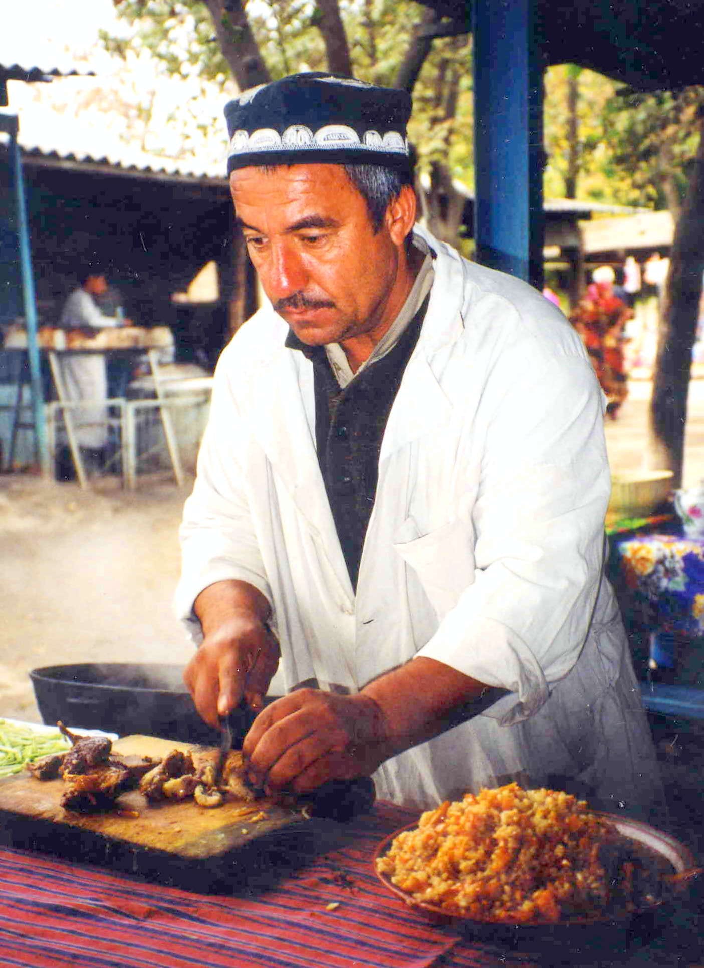 A man preparing a large pot of rice and meat