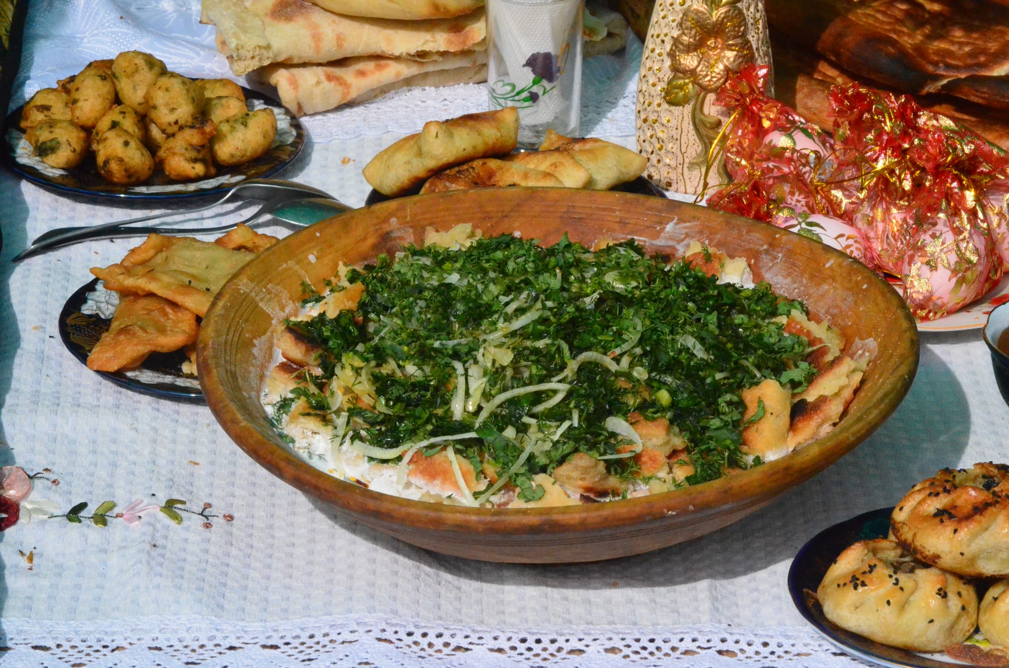 A bowl of torn flatbread soaked in a yoghurt-based sauce with onion
