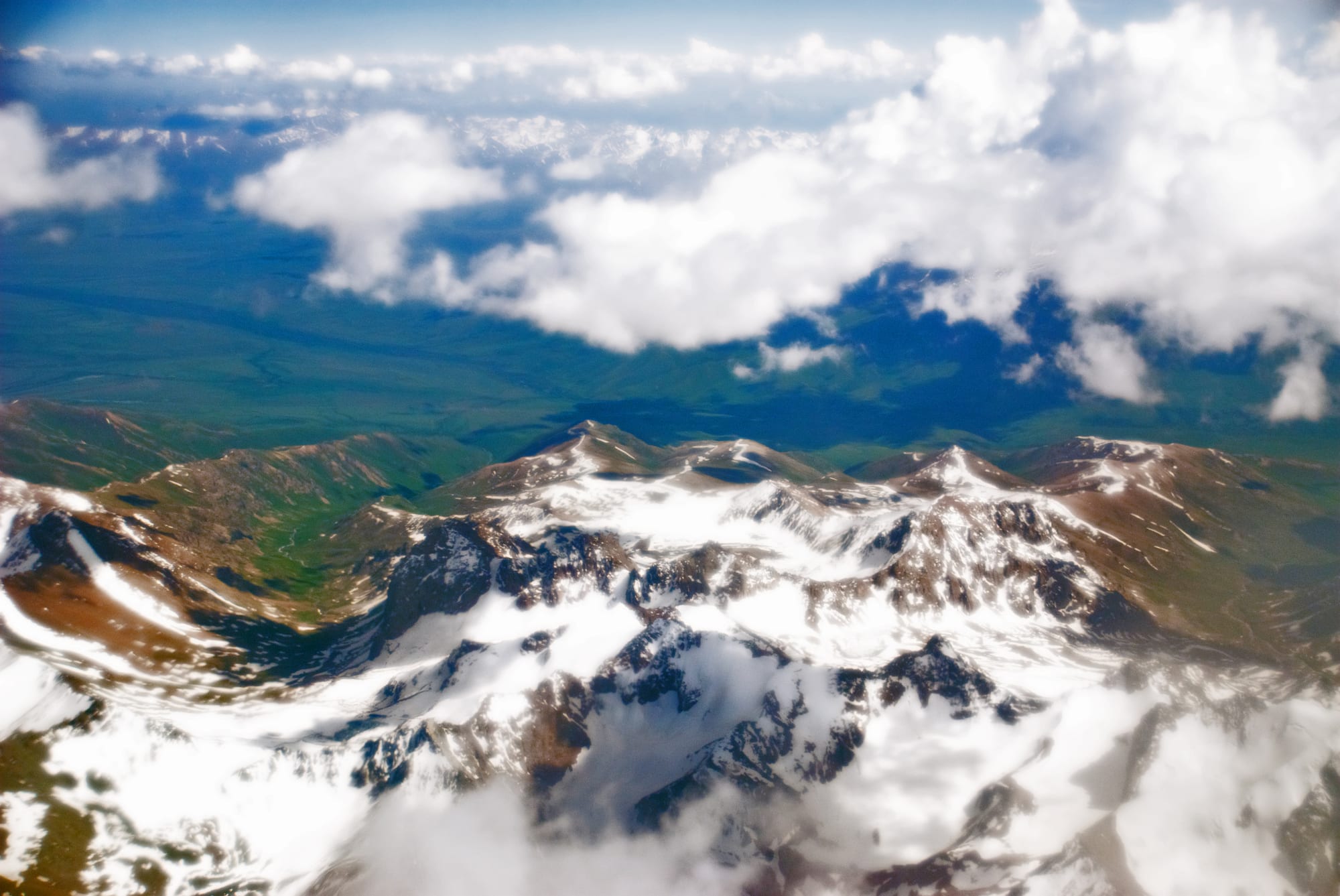 A vast, treeless high-altitude plateau of brown and ochre mountains under a deep blue sky in the Pamirs