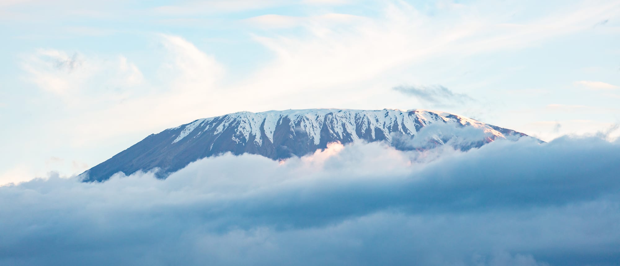 A wide view of a snow-capped mountain summit above clouds