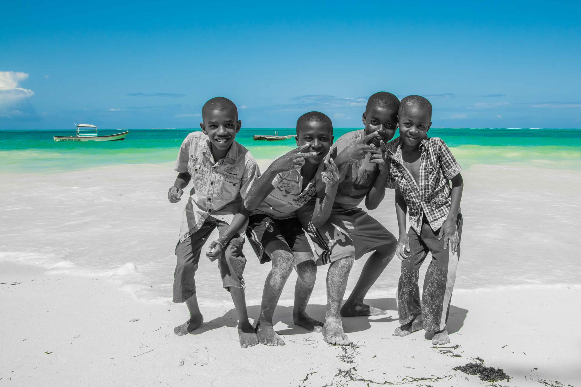 Children playing on a white sand beach beside clear turquoise water
