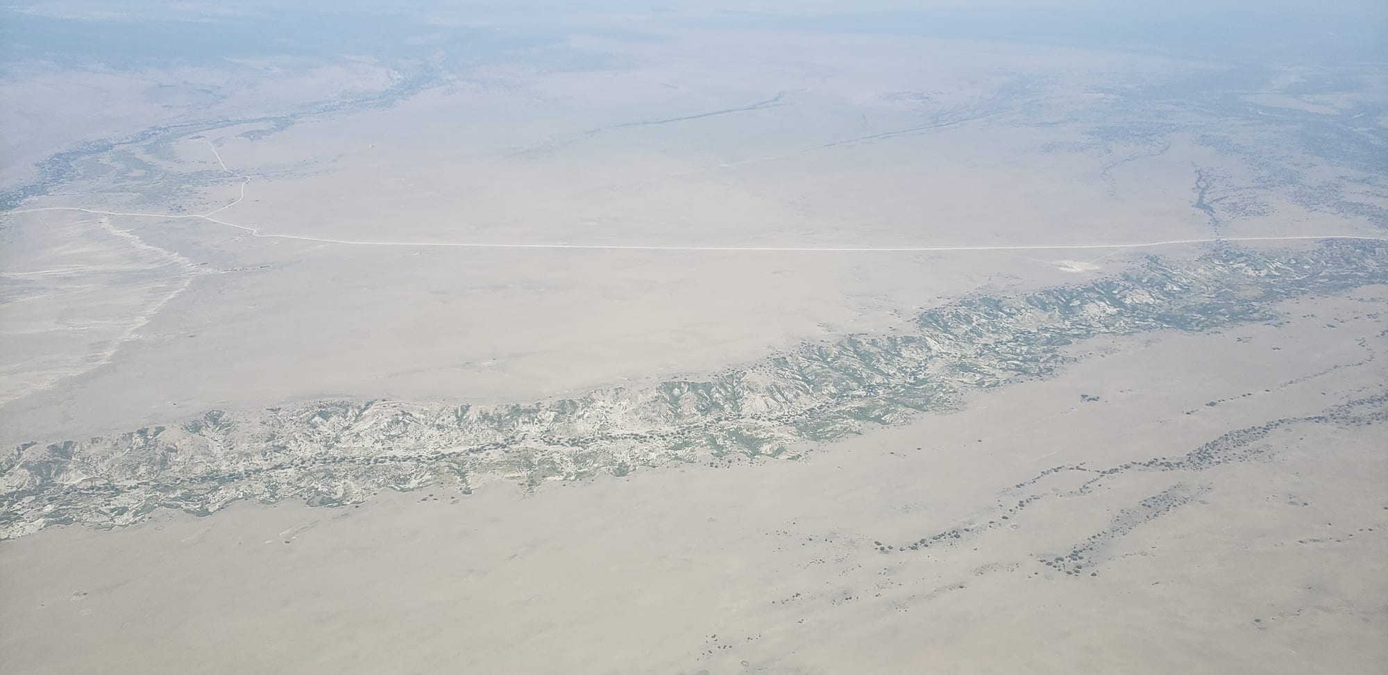 An aerial view of a deep eroded gorge cutting across a dry plain