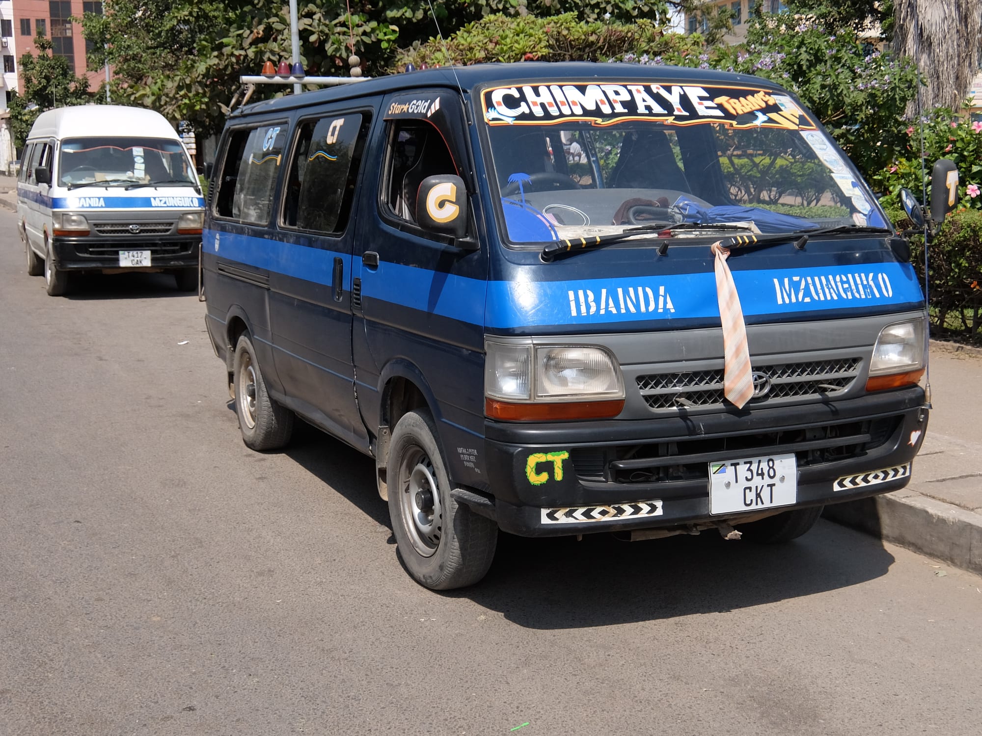 Two brightly painted minibuses with hand-lettered names parked on a street