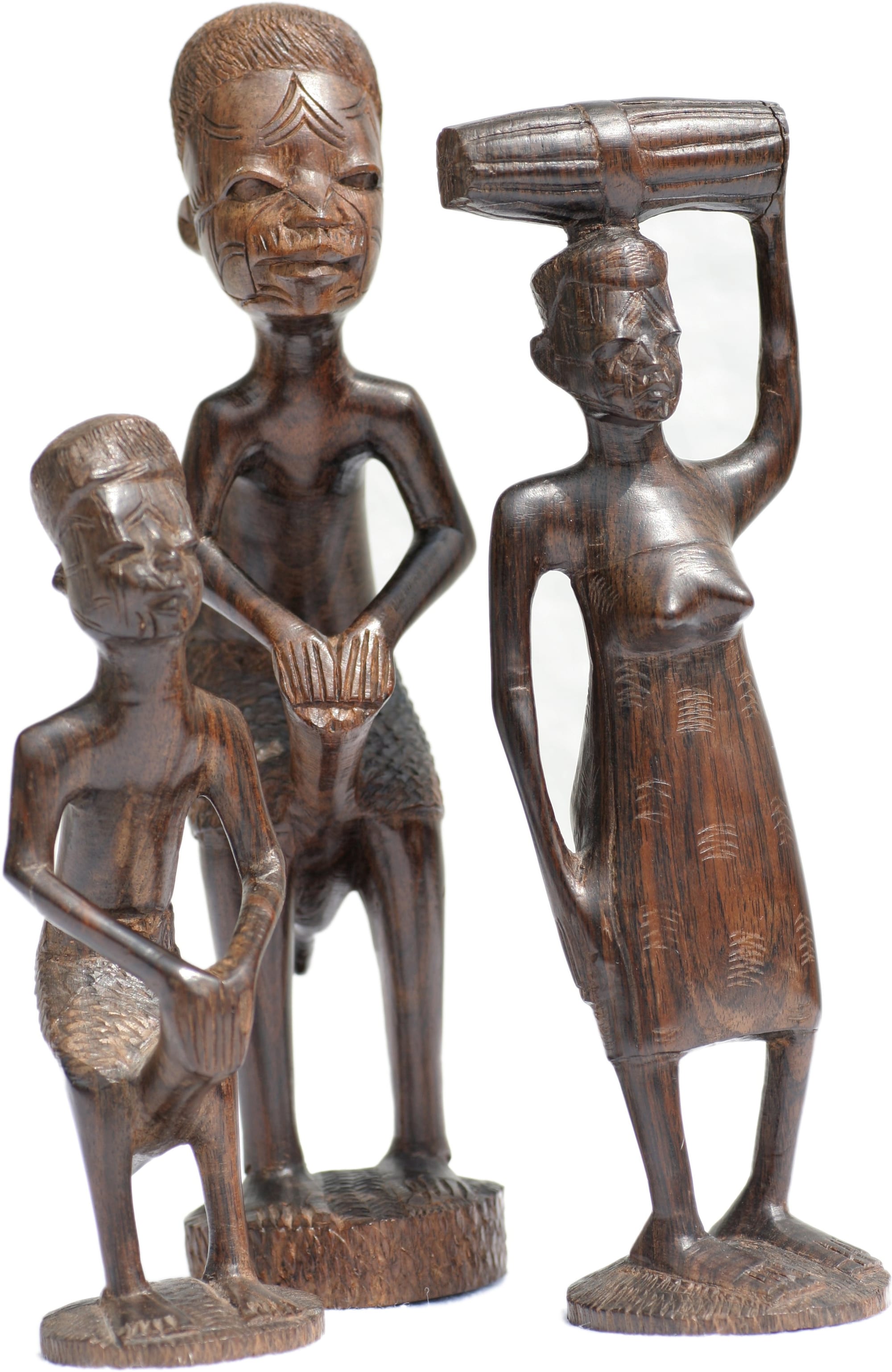 Three dark wooden carved figures on round bases, a tall man in the middle, a smaller figure in front and a woman on the right balancing a load on her head with one raised arm