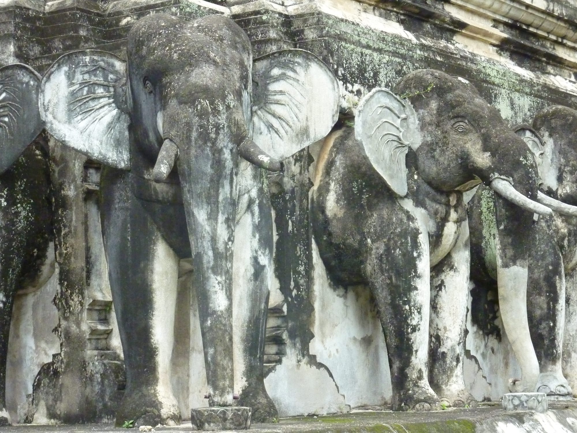 A traditional golden Buddhist temple with elephant statues at its base