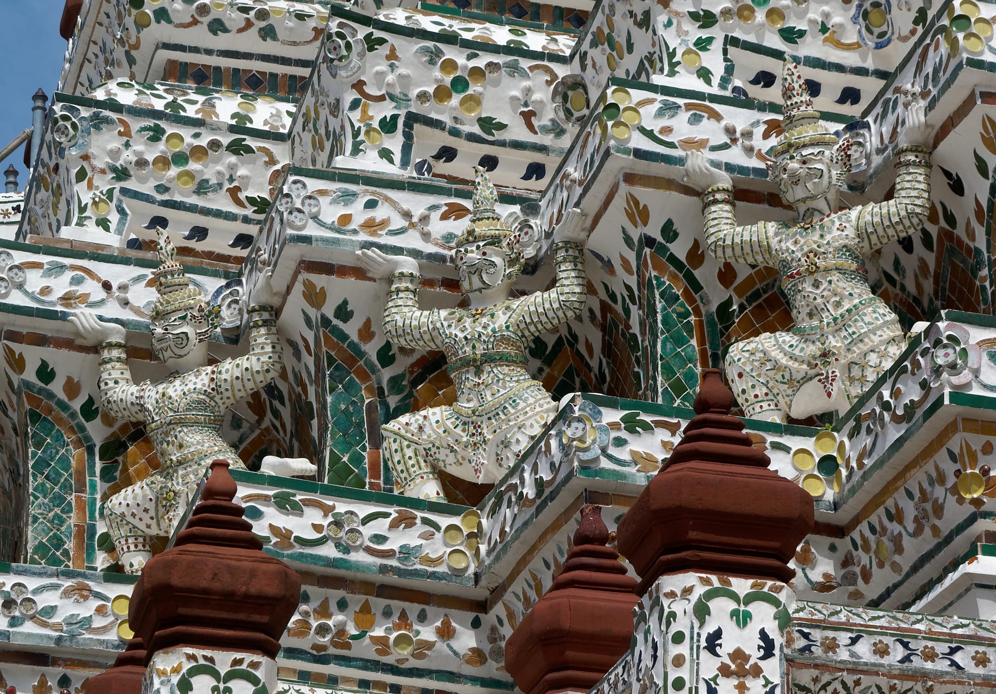 A close view of an ornate temple spire decorated with intricate porcelain mosaic