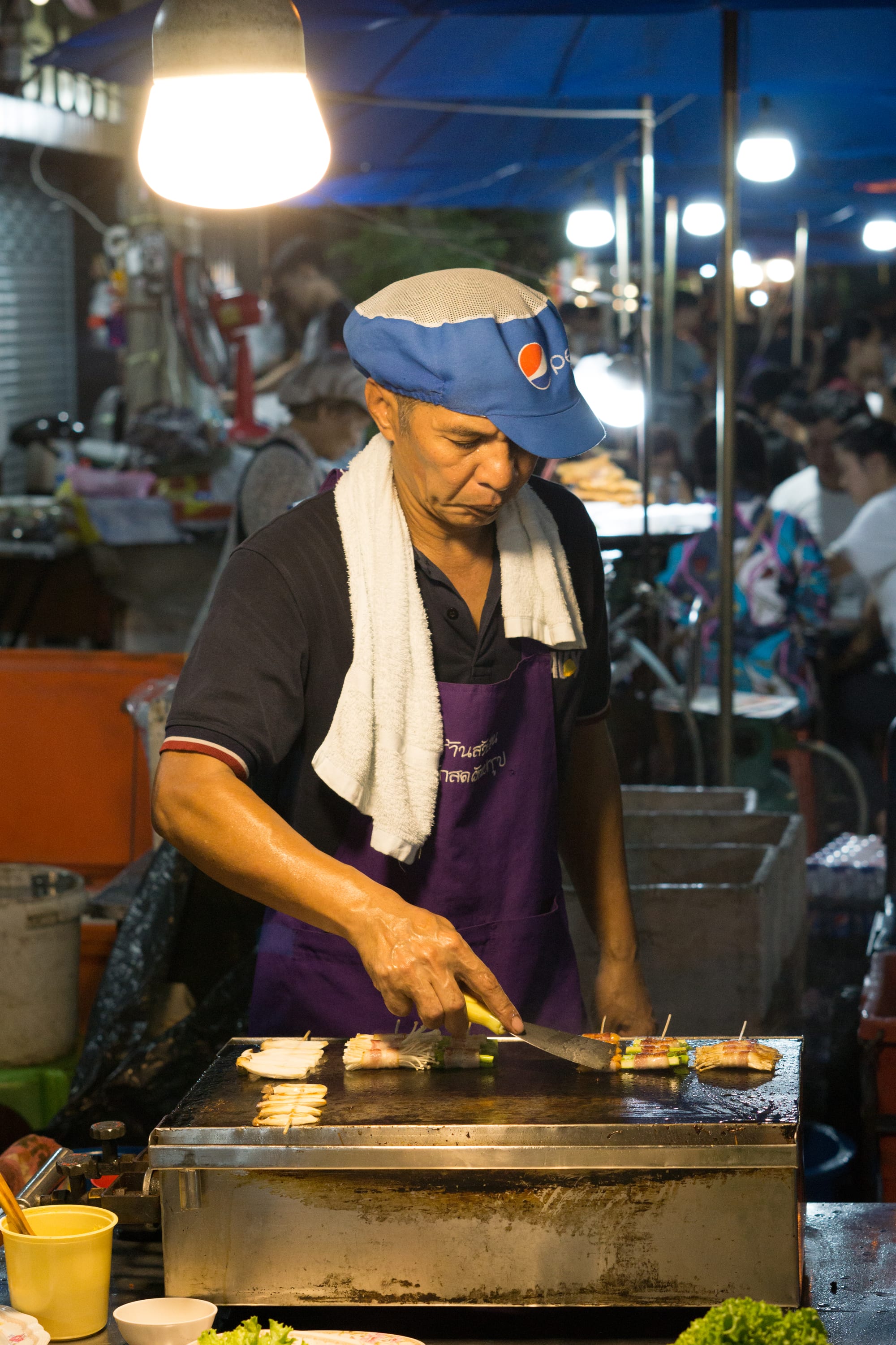 A man preparing food at a crowded market stall