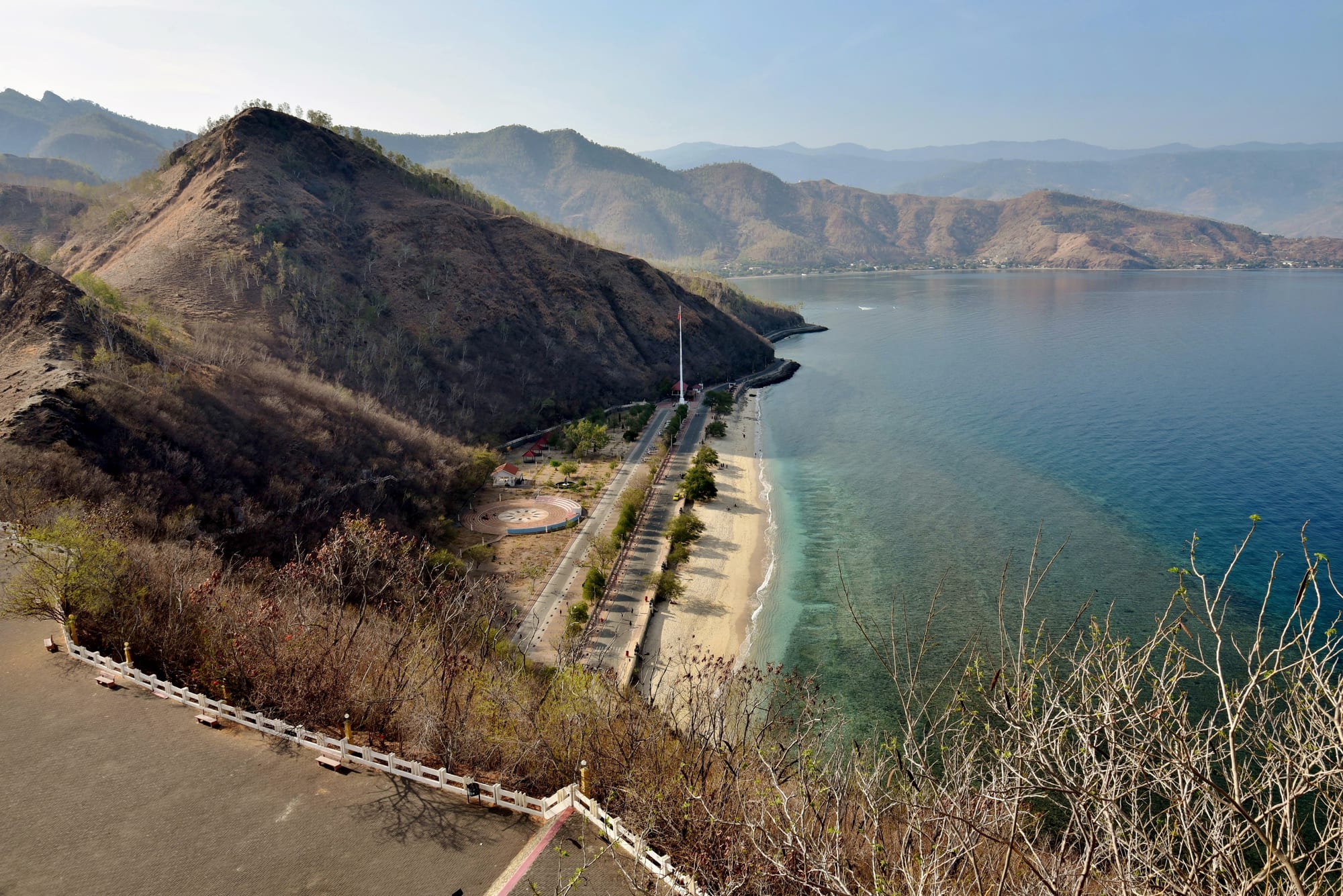 A beach beneath a hillside statue overlooking the ocean