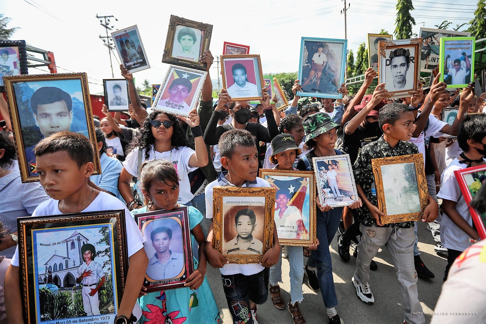 Timorese people carrying flags and photographs in a memorial procession through Dili for the Santa Cruz victims