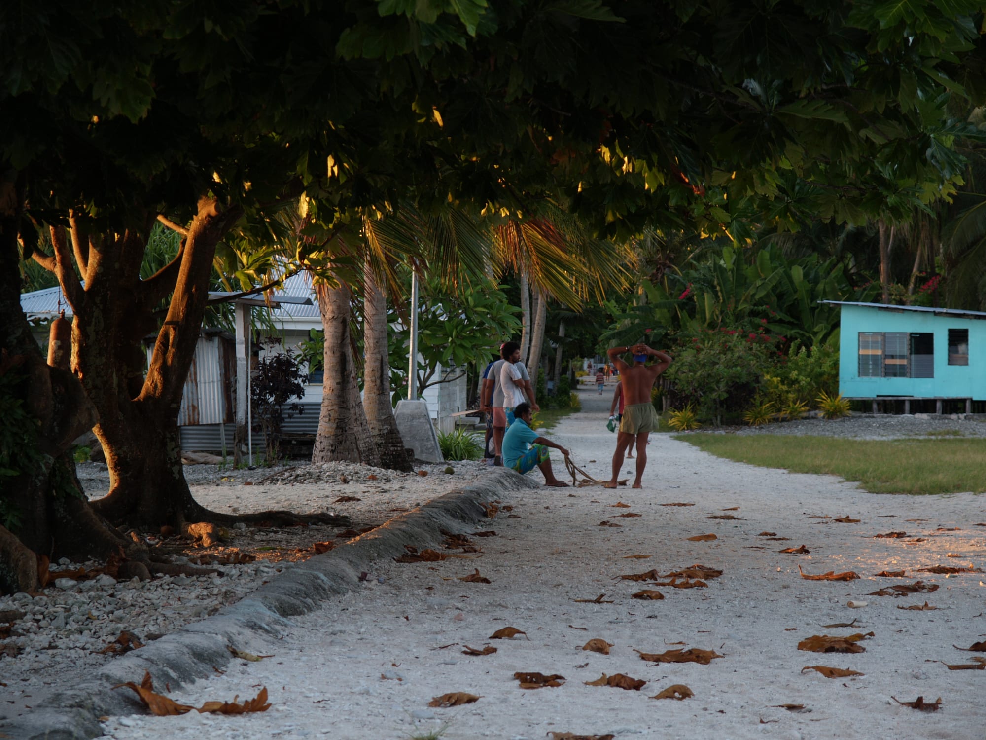A quiet sandy village street at dawn lined with simple houses