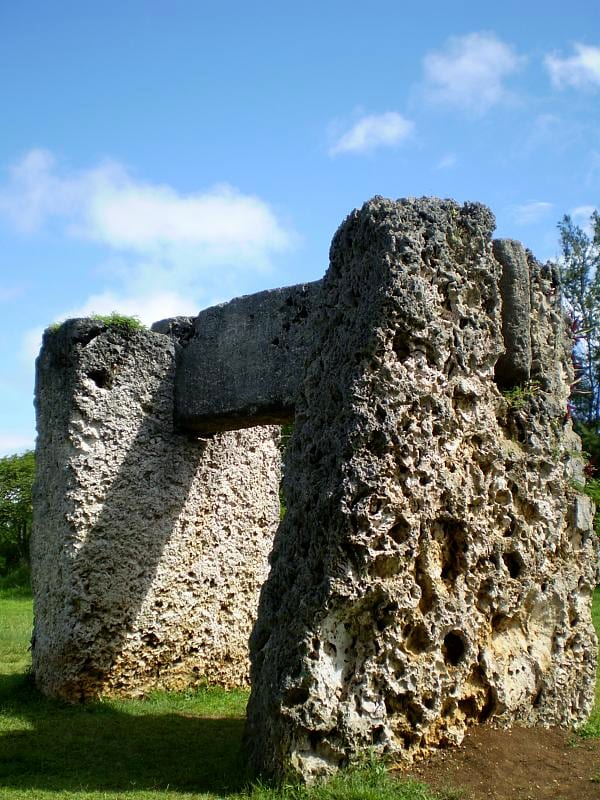 A massive ancient stone trilithon standing in an open field