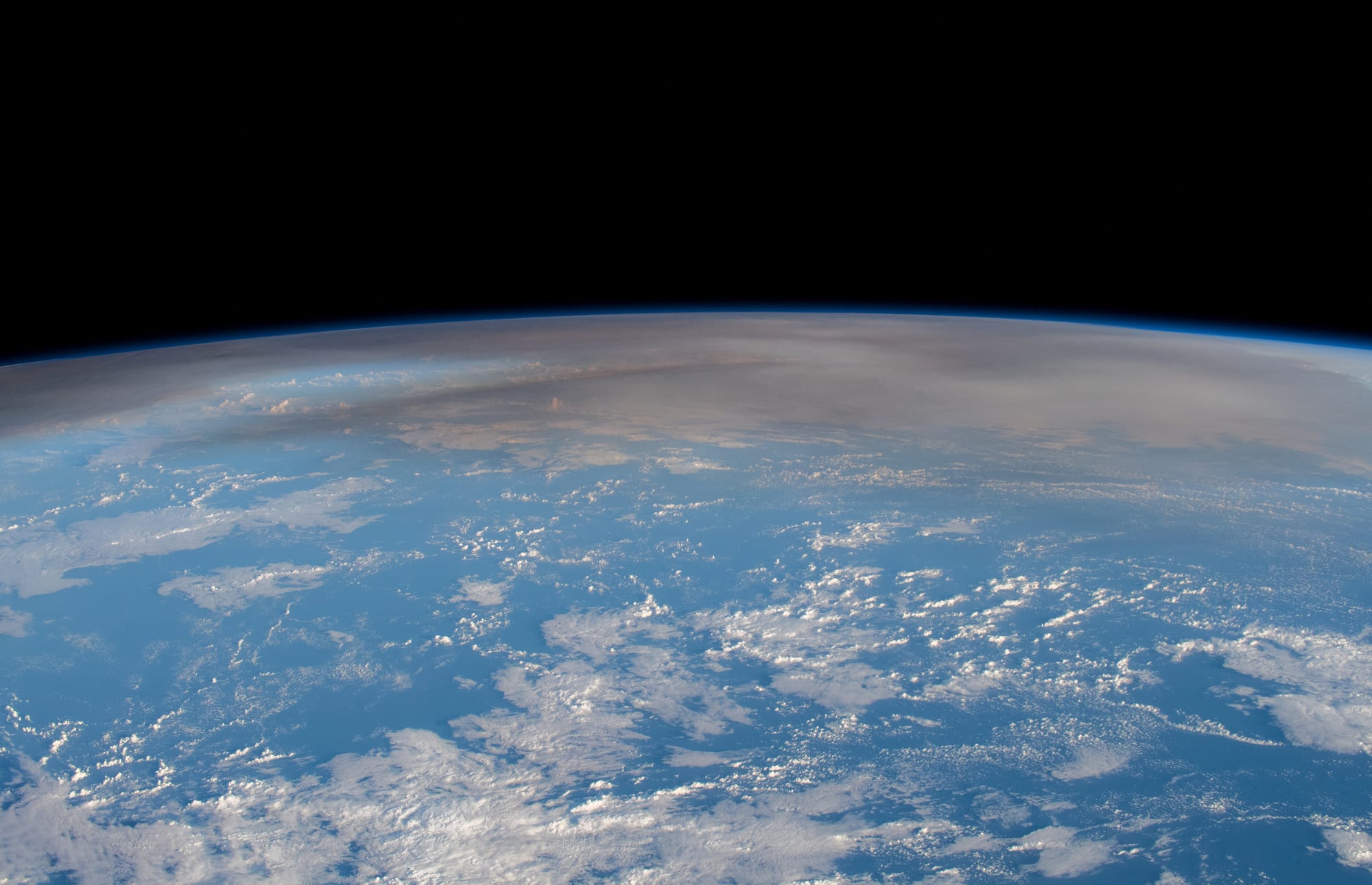 A vast circular cloud of ash and steam spreading over the ocean, photographed from the International Space Station