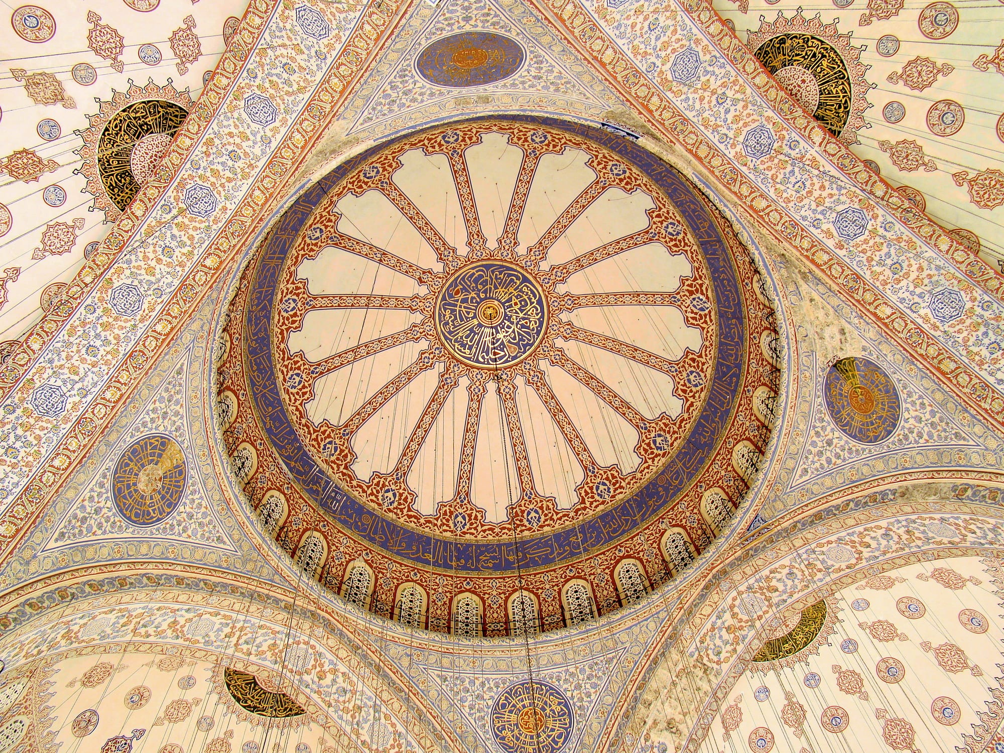 An ornate mosque interior ceiling covered in blue tilework