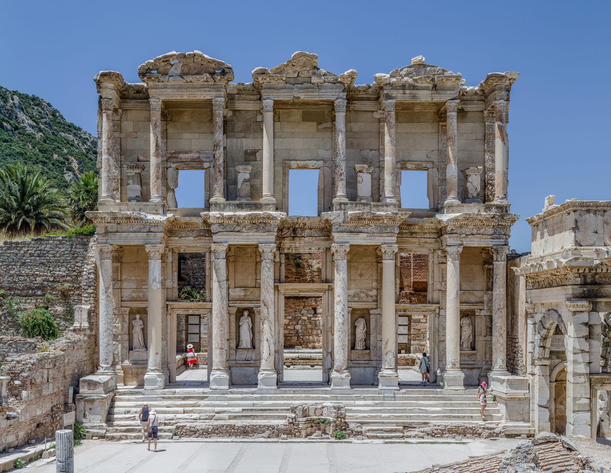 The ornate facade of an ancient Roman library among ruined columns