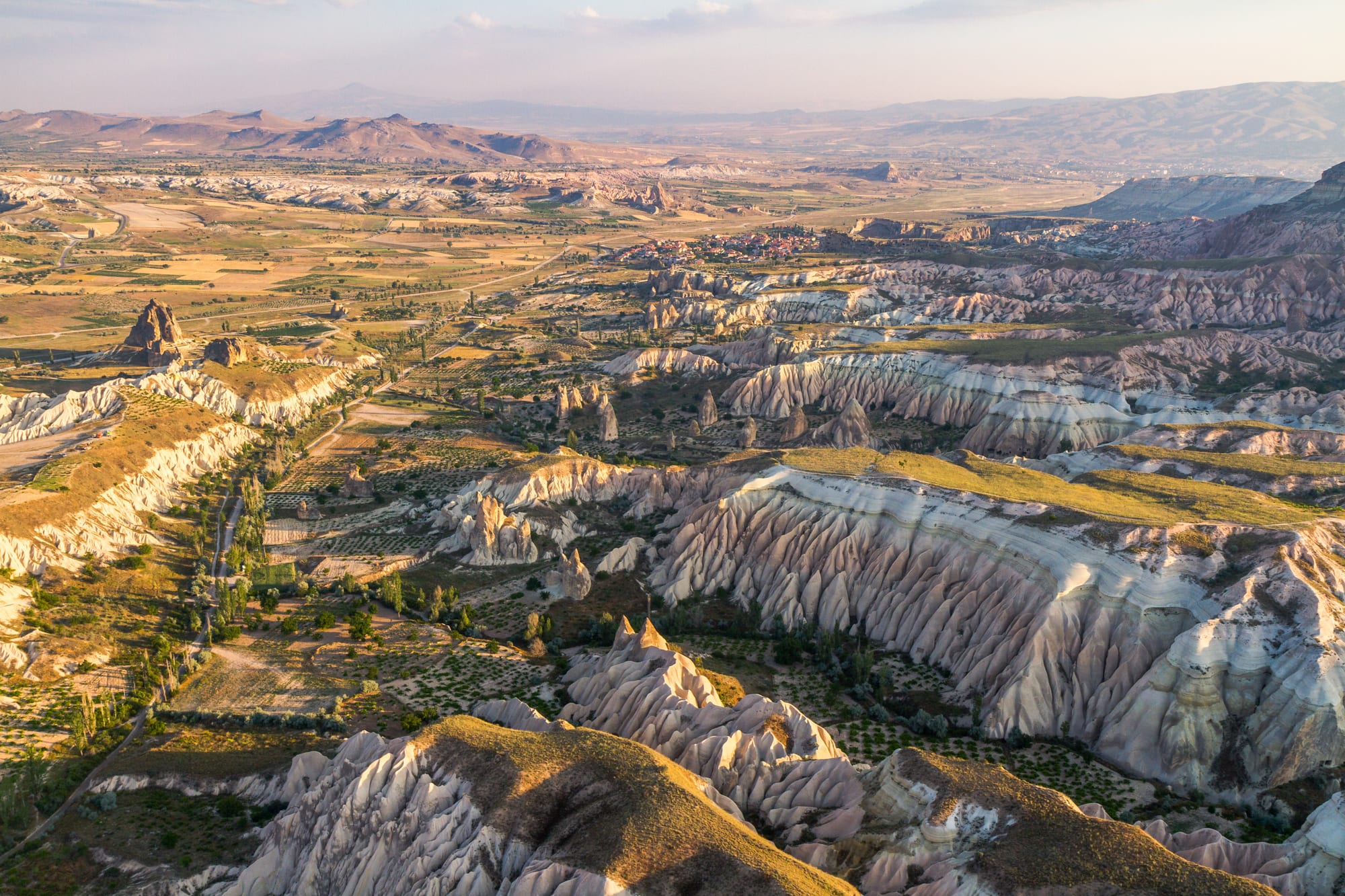 A dramatic aerial view of eroded rock valleys and cone-shaped formations