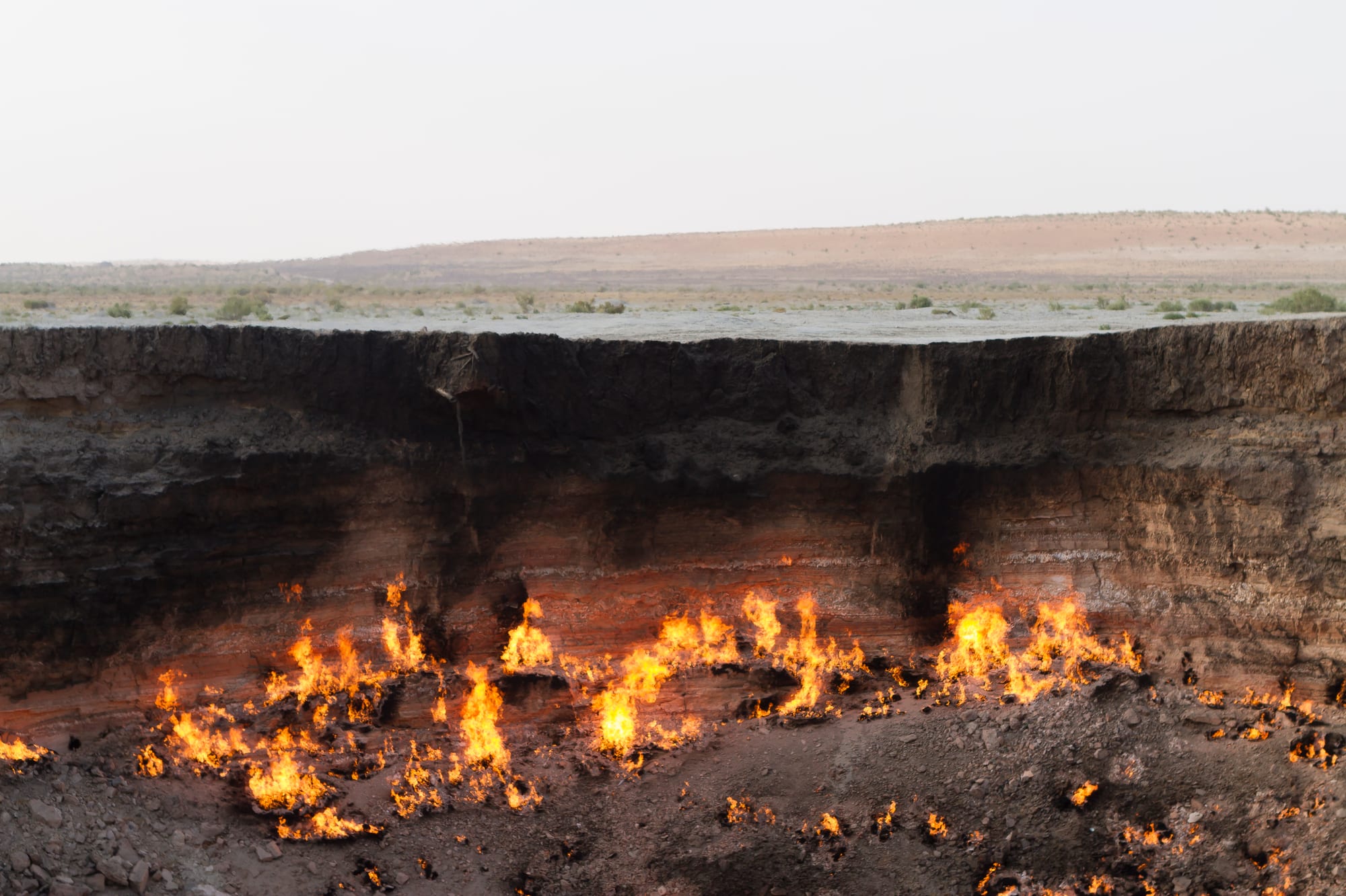 A massive crater filled with continuously burning fire in a desert landscape at night