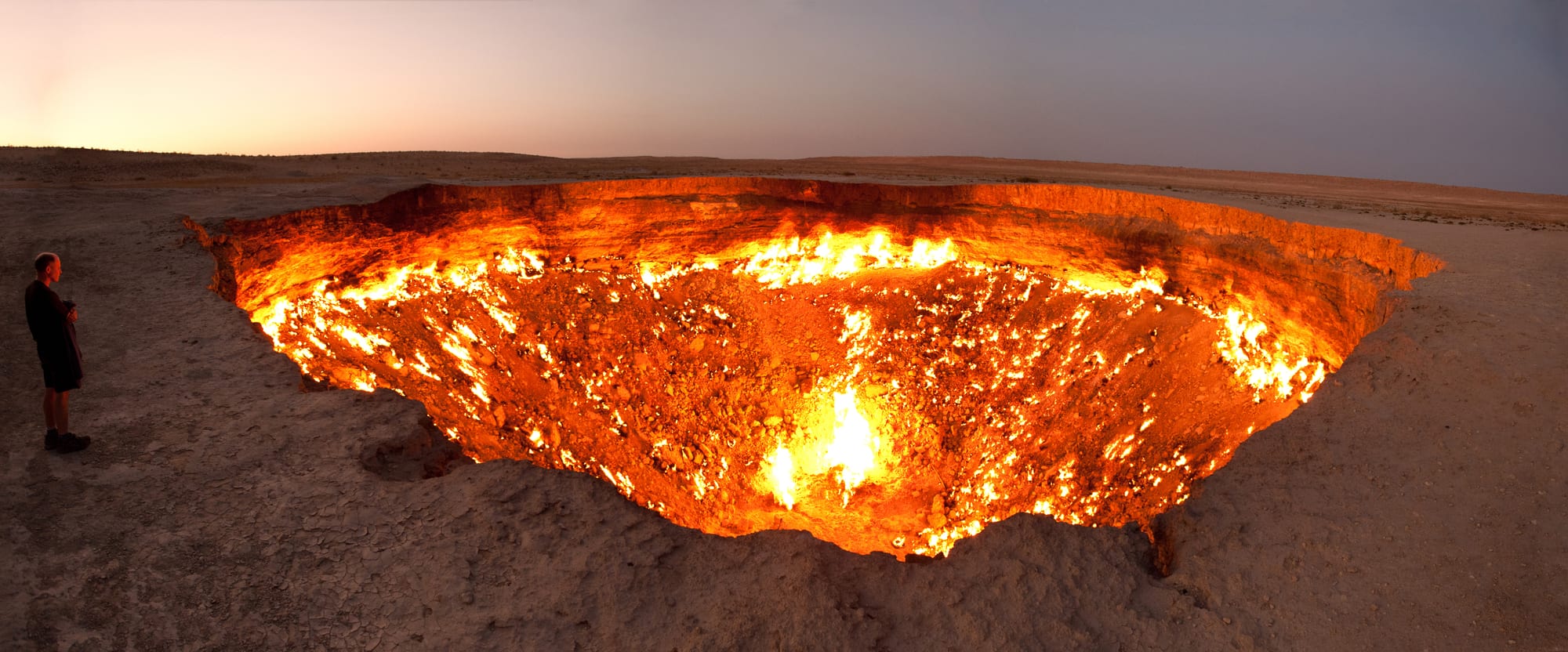 A massive glowing crater of fire in a dark desert at night