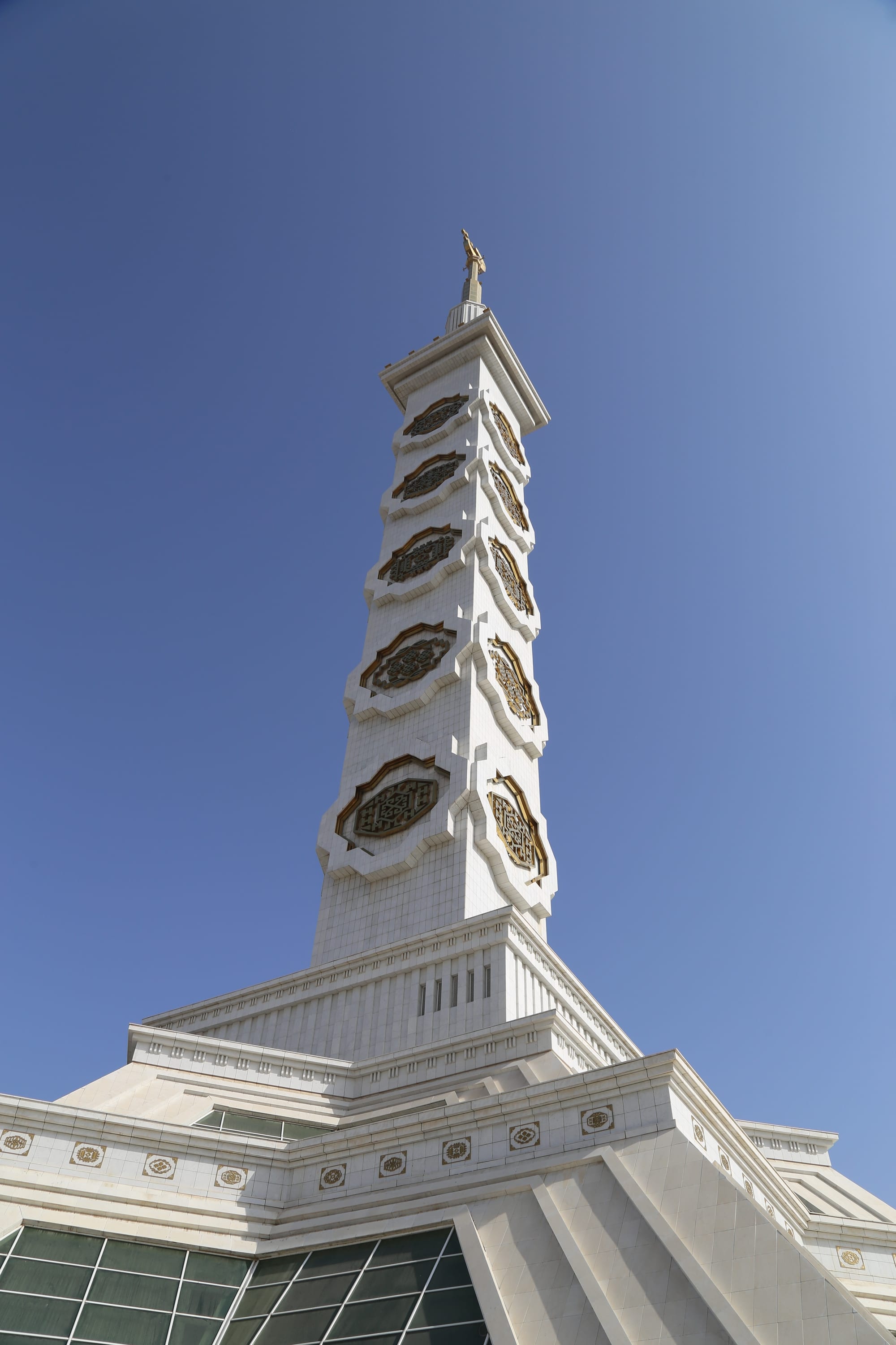 A very tall white tower topped with a gold star and crescent rising above Ashgabat