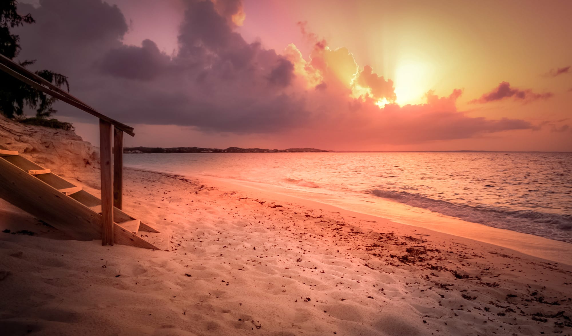 A long white sand beach at sunset with calm turquoise water