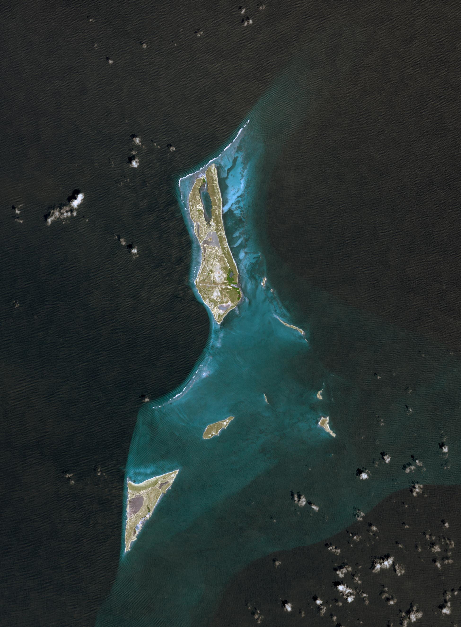 A satellite view of small islands surrounded by turquoise water and reef