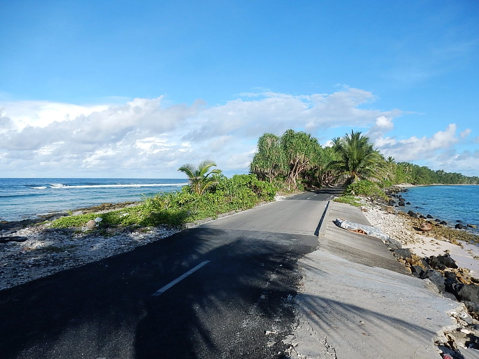 A paved road running along the narrowest stretch of Funafuti atoll, with the open ocean on one side and the lagoon on the other
