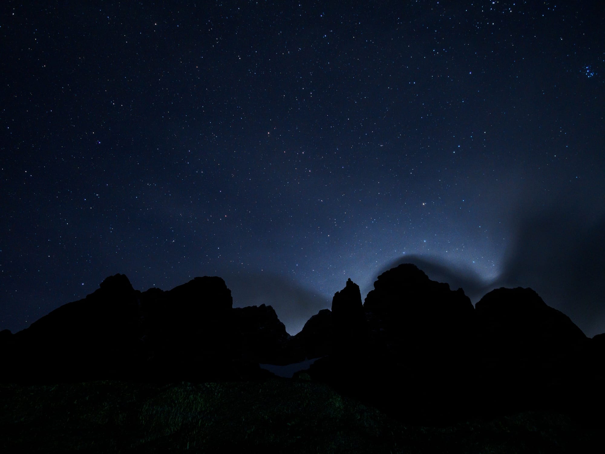 A dramatic mountain peak silhouetted against a night sky