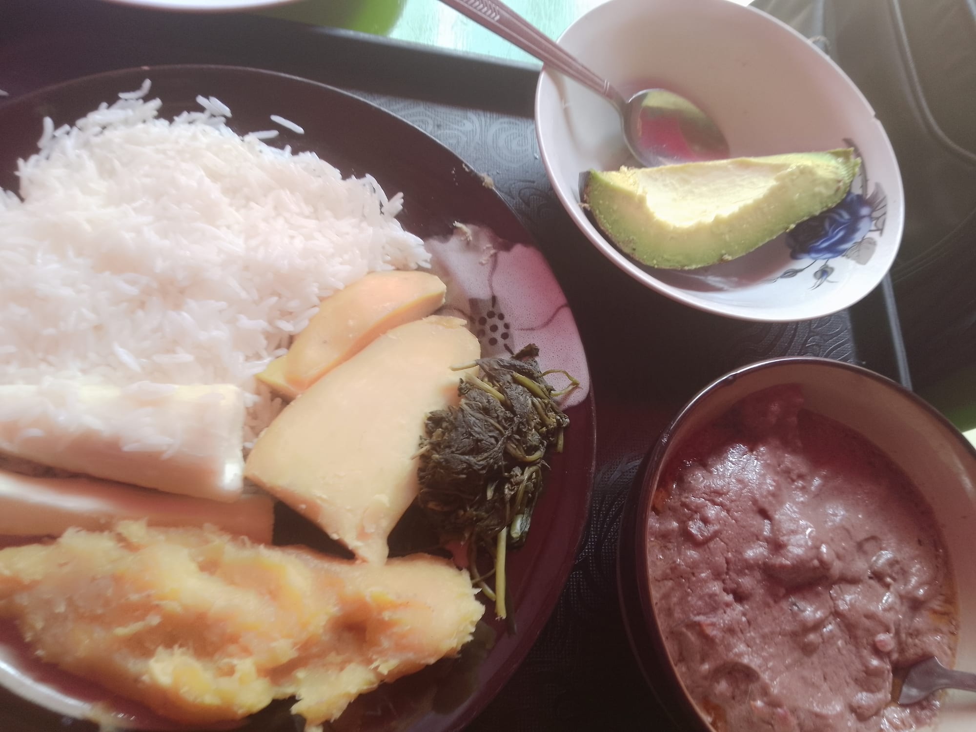 A spread of Ugandan dishes including mashed banana, rice and vegetables