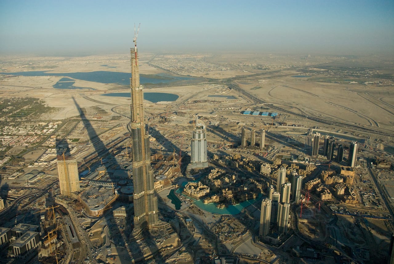 An extremely tall, slender skyscraper rising above a city skyline