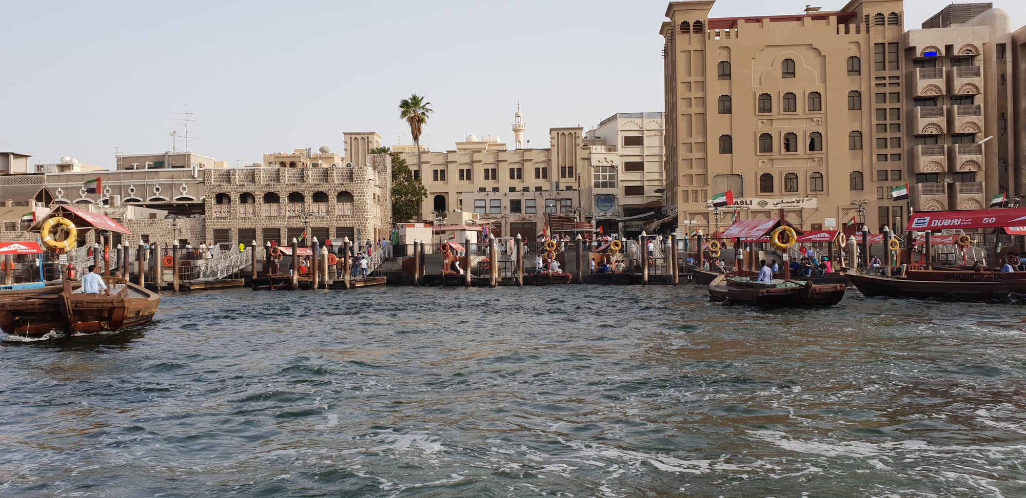 Wooden trading dhows moored along both banks of the Dubai Creek with low buildings behind