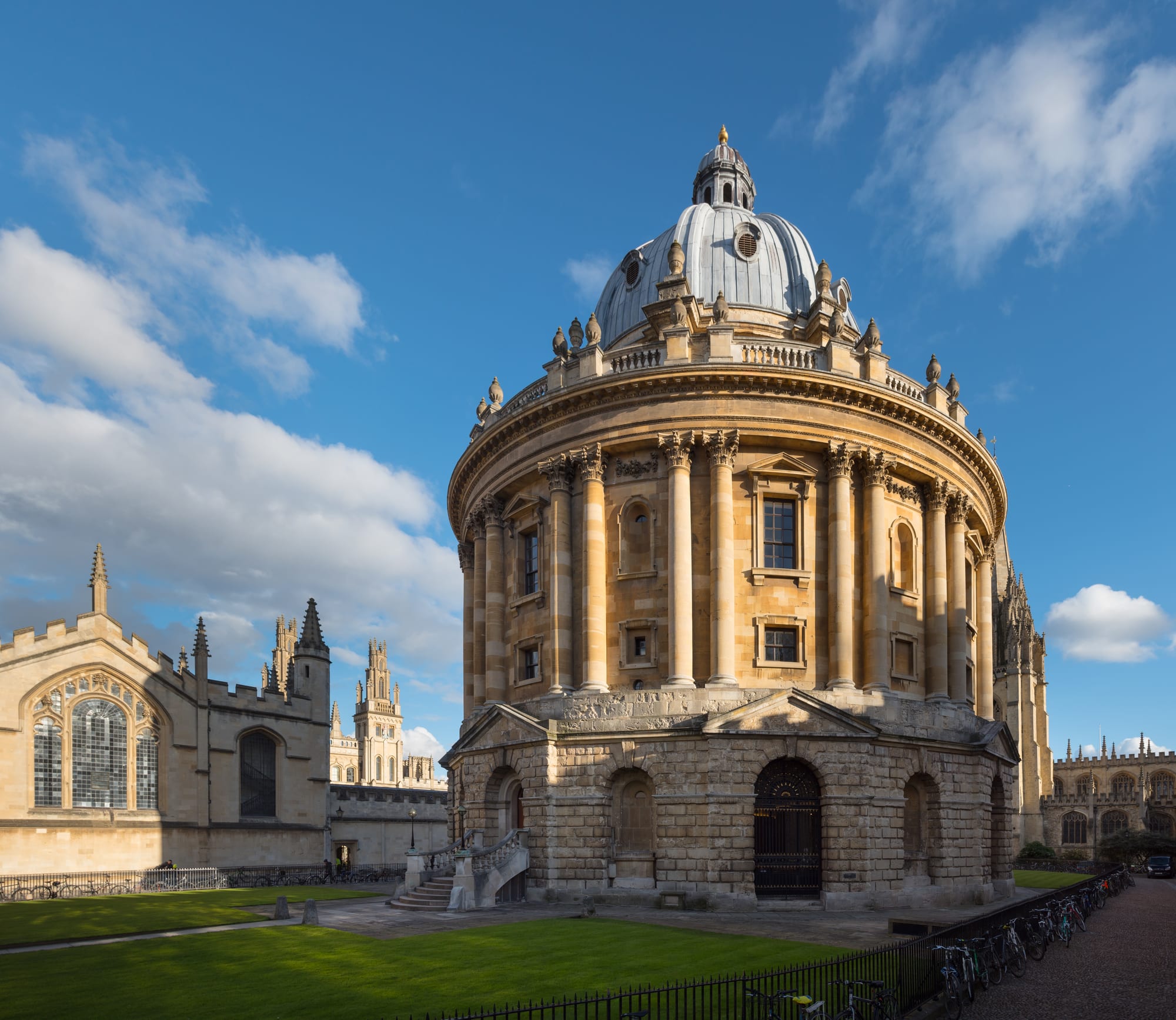 A round, domed classical library building beside Gothic college spires