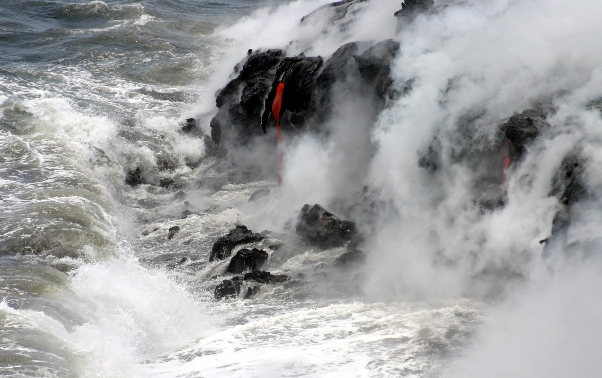 Molten lava flowing into the ocean, creating steam