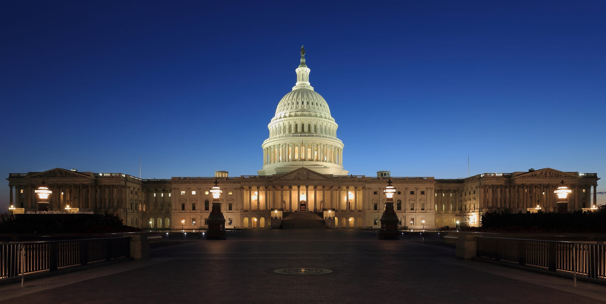 The domed United States Capitol building lit against a deep blue dusk sky