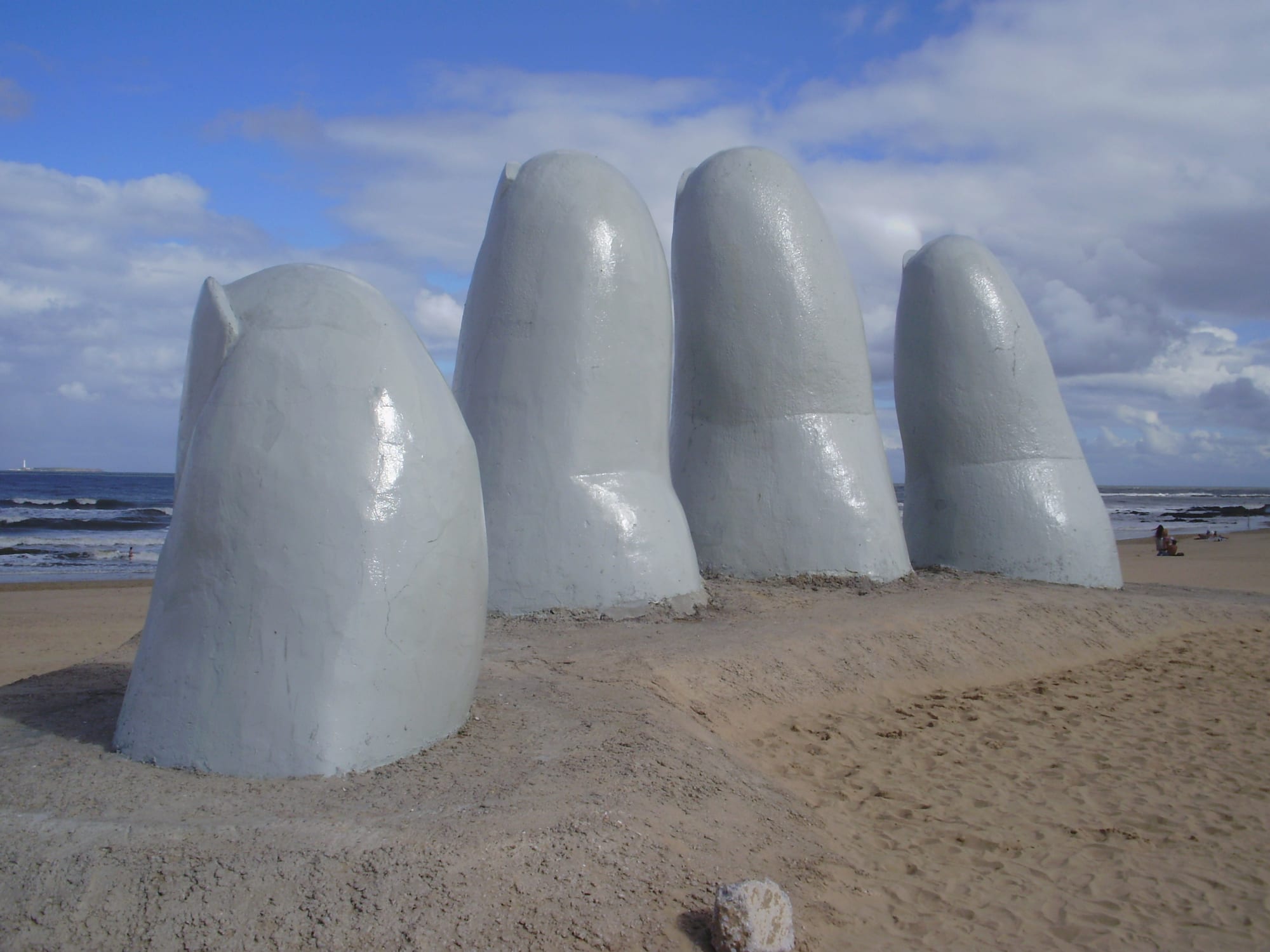 A giant sculpted human hand emerging from beach sand